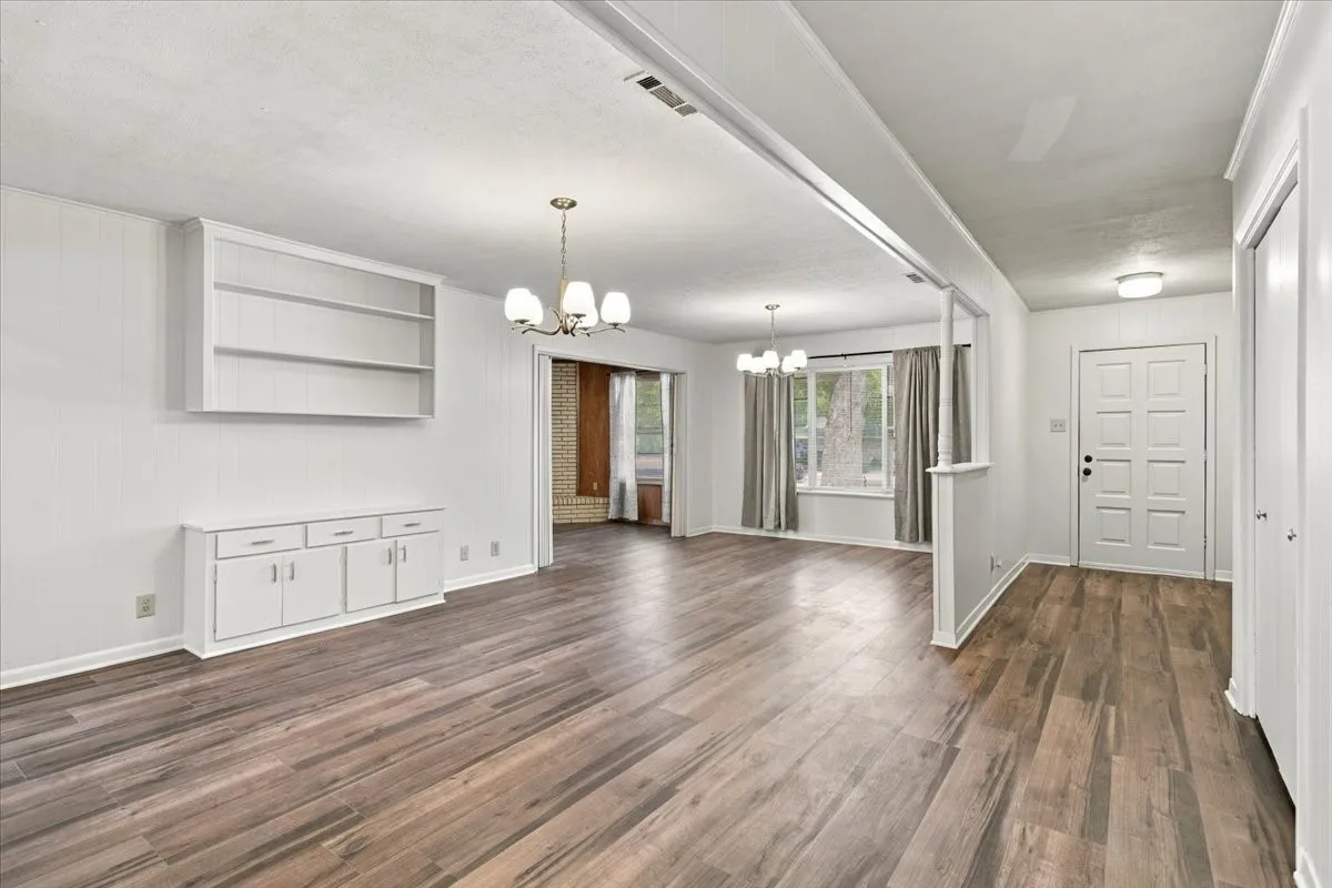View looking towards front door; open concept dining & living area with built in shelves and cabinets; large storage closet on right.  New vinyl plank flooring