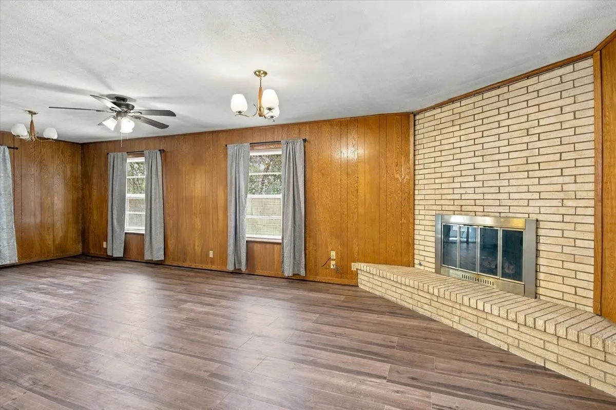 Den with new vinyl plank flooring, Wood Burning Brick Fireplace, lots of windows for plenty of natural sunlight, built in book shelves, ceiling fan.  Nice large room flows effortlessly into kitchen and living/dining areas.