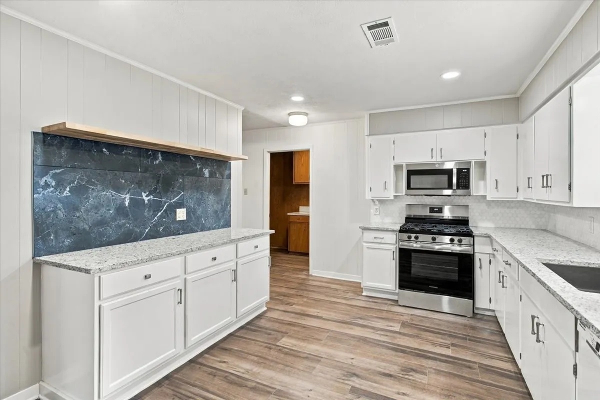 Newly remodeled & spacious kitchen with NEW: vinyl plank flooring, gas range, microwave, lovely granite counters, farm sink, tile backsplash, kitchen cabinet hardware; fresh paint on cabinets & walls, ; coffee bar with accent wall and floating shelf, canned lighting; dishwasher.  Large, really pretty kitchen!!