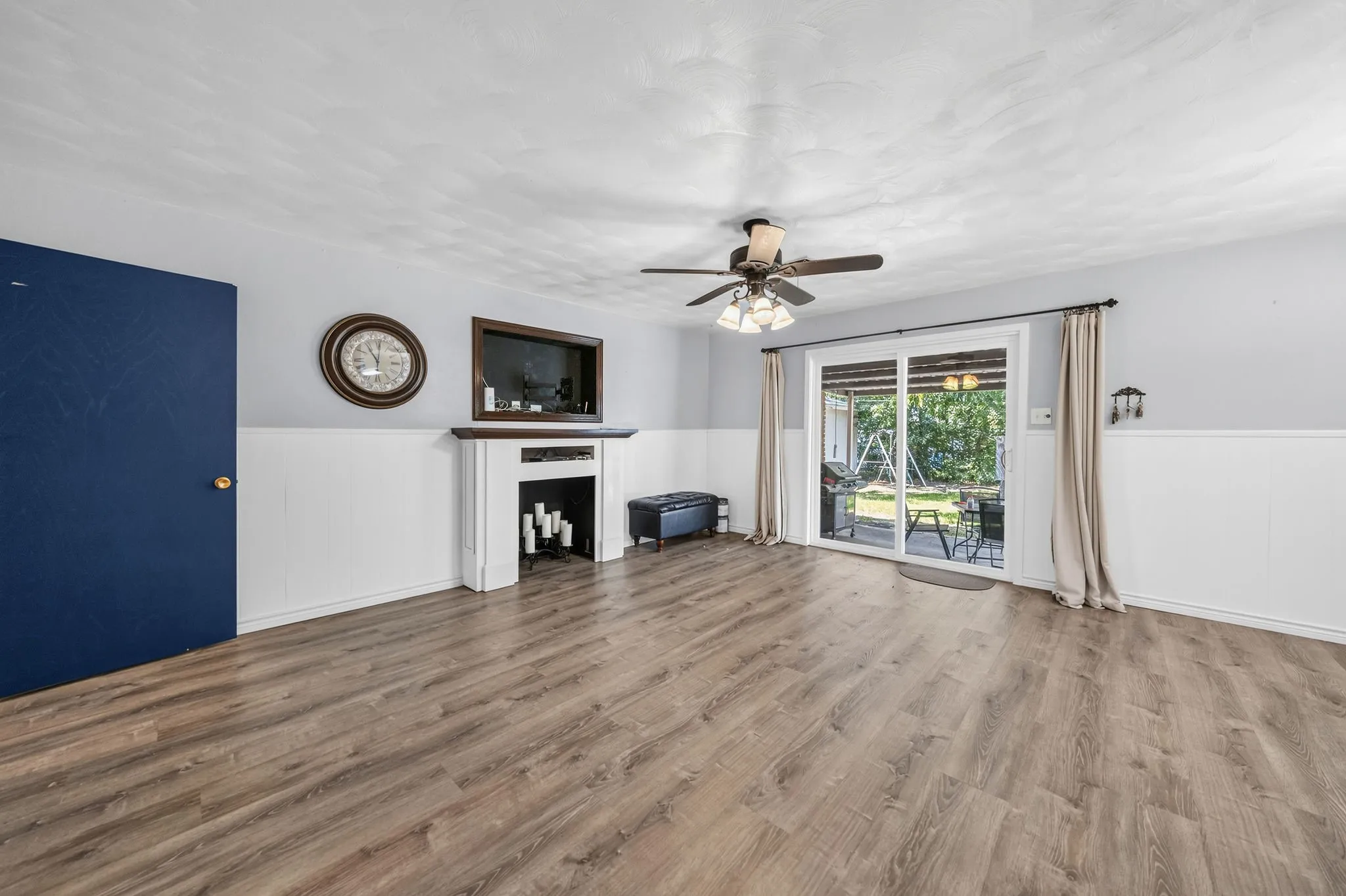 Spacious room featuring wood-finish flooring, wainscoting, and a built-in decorative fireplace