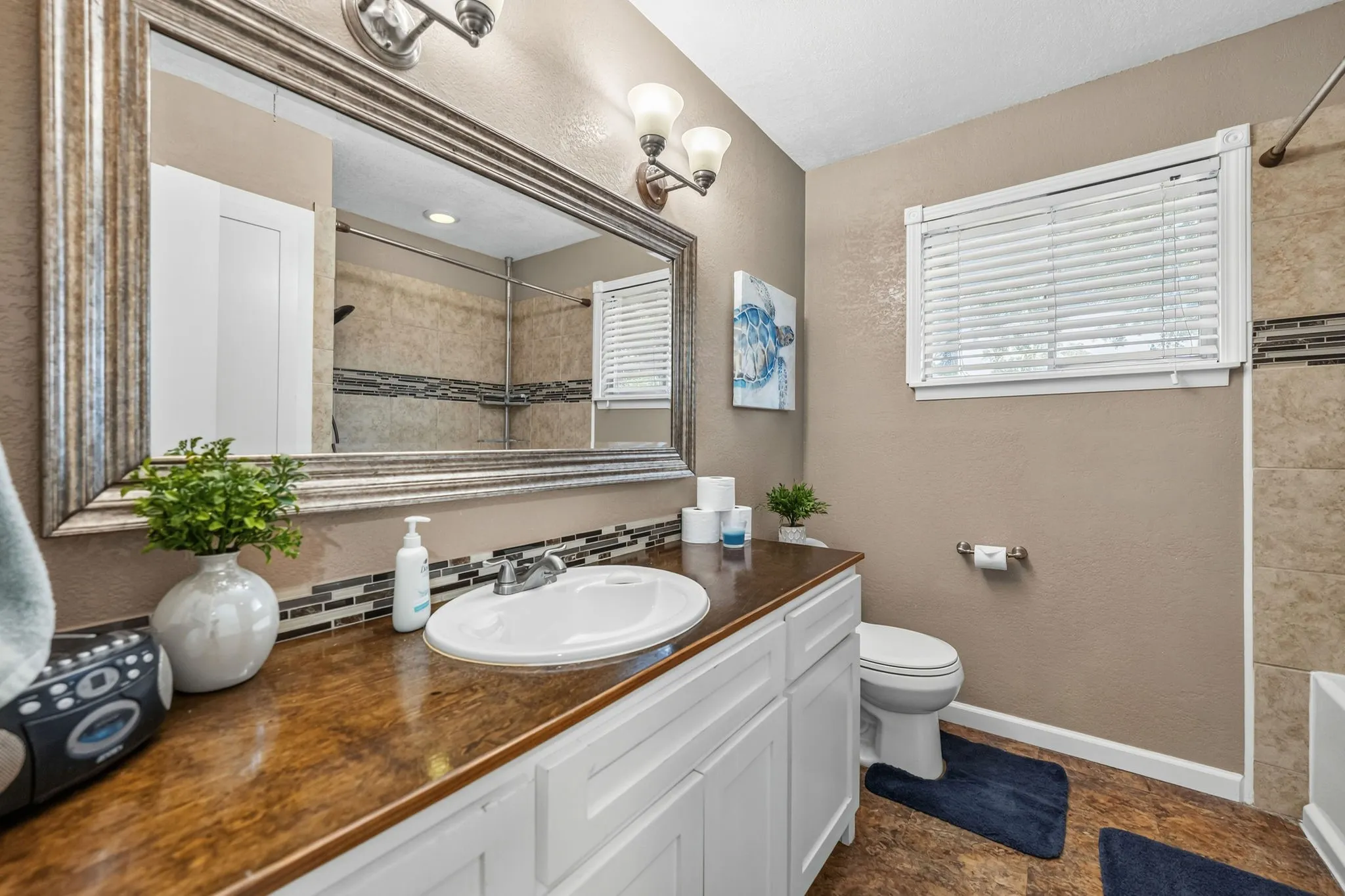Bathroom featuring a vanity with a dark wood-finish countertop, white cabinetry, and a drop-in sink