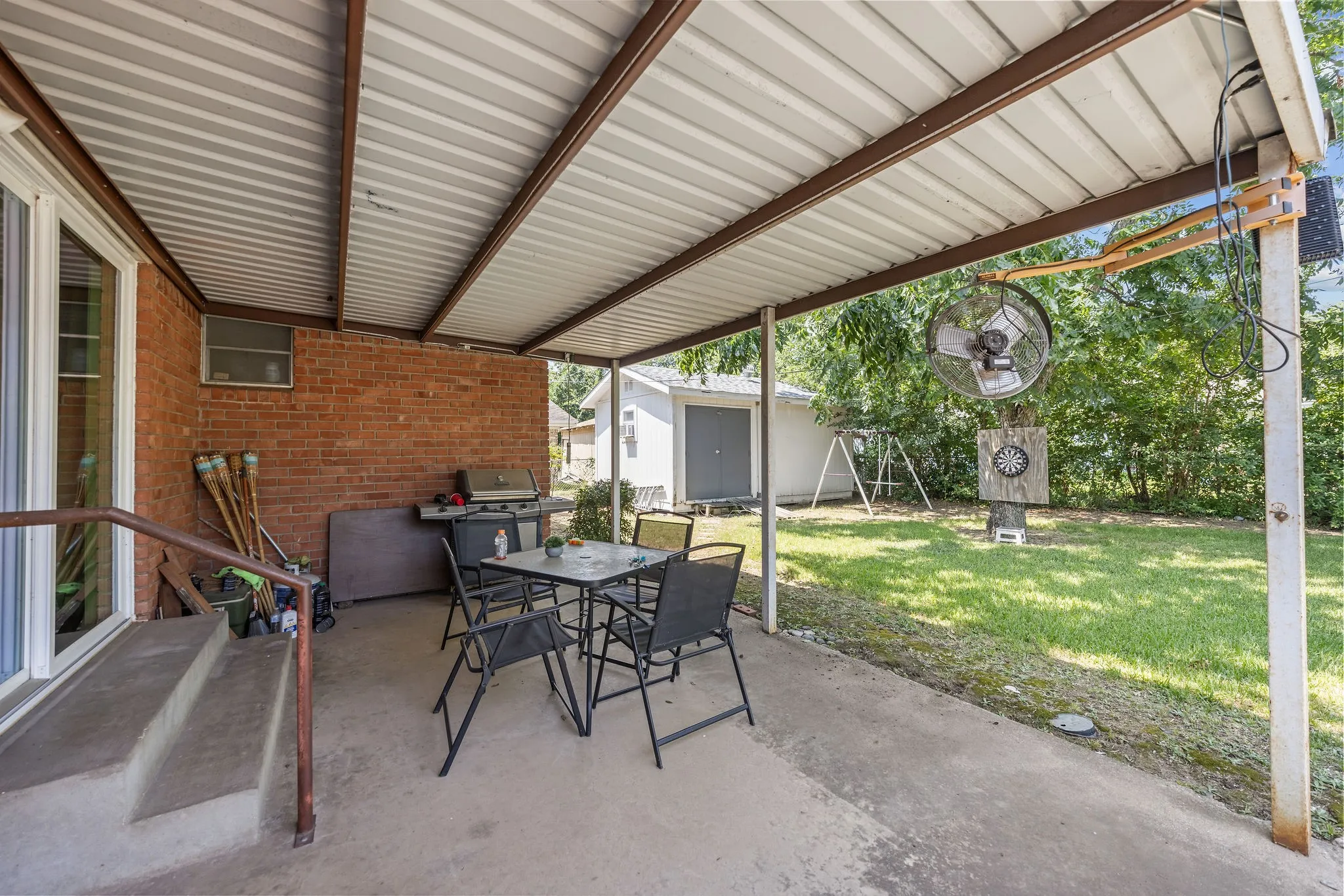 Covered patio with concrete flooring, brick exterior wall, and direct yard access