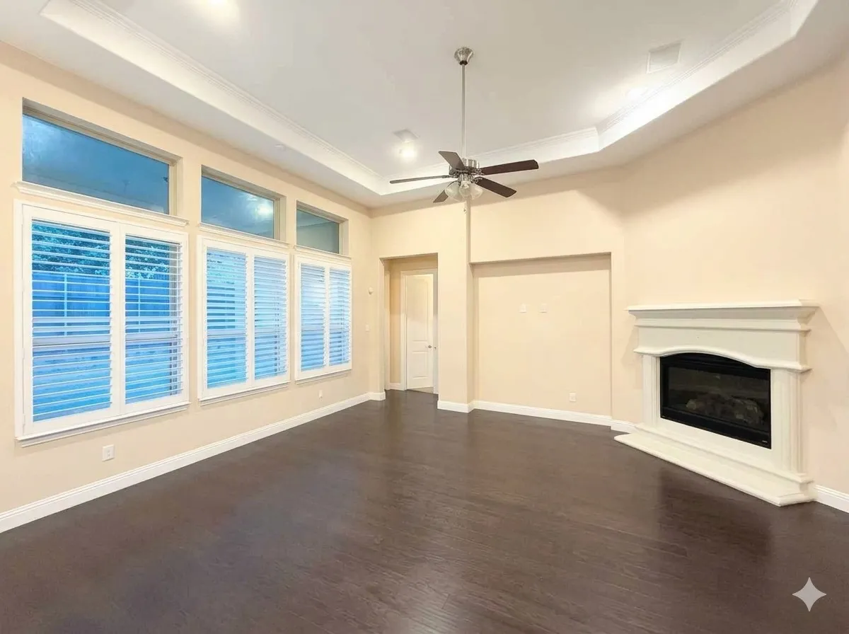 Tray ceiling with crown molding, dark wood-finish flooring, white plantation shutters, electric fireplace with white mantel, and ceiling fan