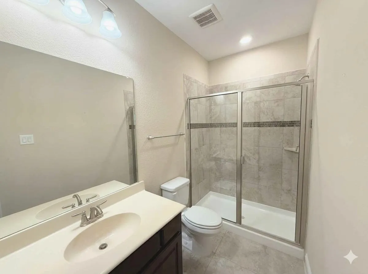 Vanity with integrated sink and chrome faucet, large frameless mirror, and overhead vanity lighting