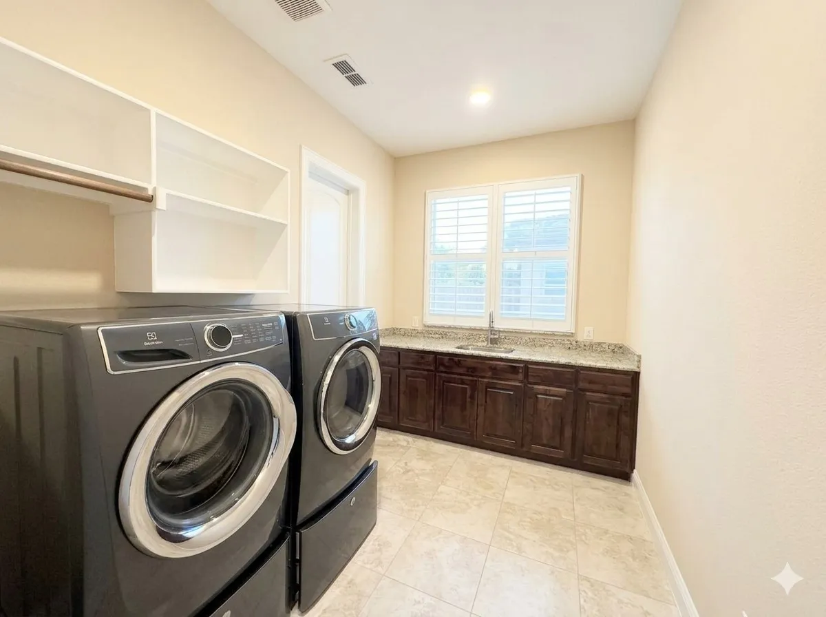 Laundry room featuring tiled flooring, built-in cabinetry with a countertop and sink, window with plantation shutters, and overhead shelving