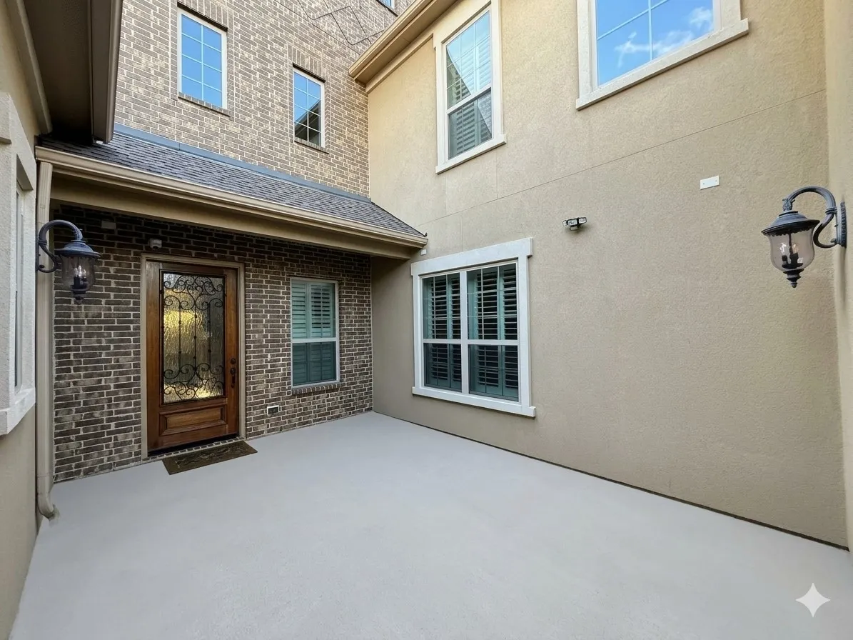 Entry with a wood door featuring decorative wrought iron and glass, brick and stucco exterior, covered porch, and exterior sconce lighting