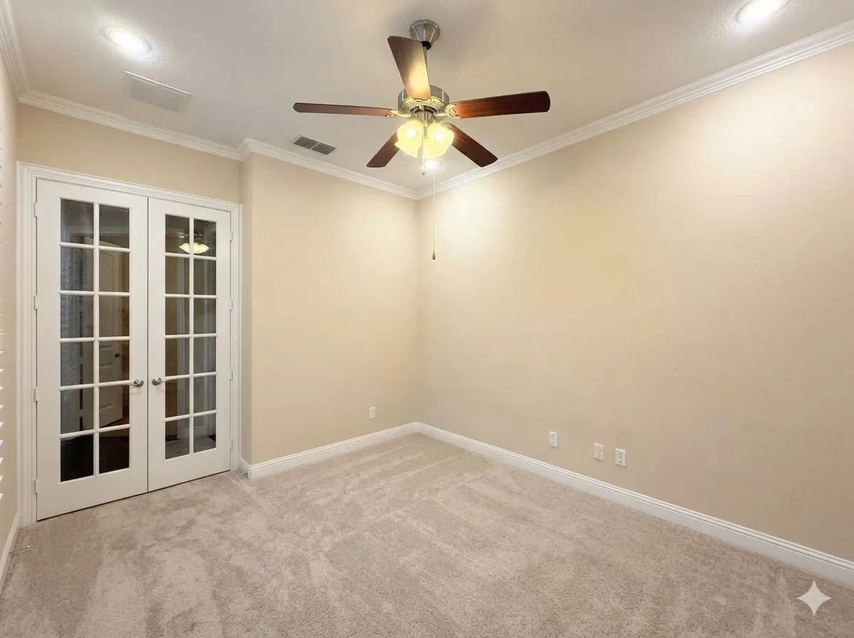 Neutral tone wall paint, light-colored carpeting, white French doors with glass panes, crown molding, and a ceiling fan with integrated lighting