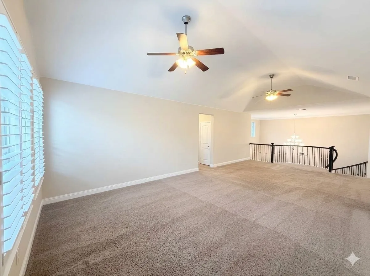 Vaulted ceiling with dual ceiling fans, neutral carpeting, and a white balustrade with dark wood accents overlooking a lower level