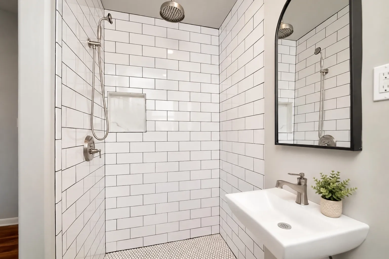 Walk-in shower with white subway tile, mosaic tile flooring, and a built-in niche