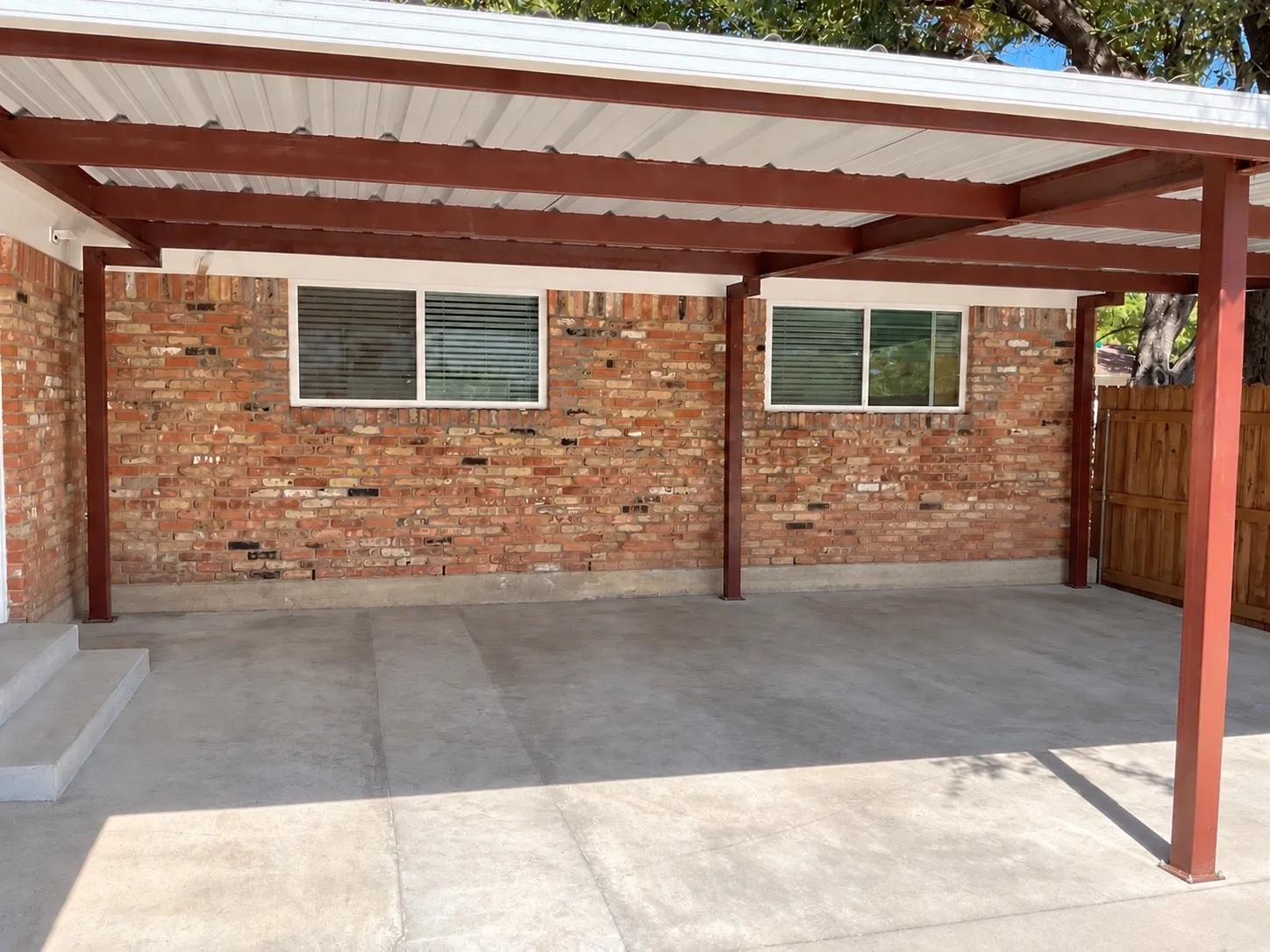 Wood-finish flooring, wood cabinetry, stainless steel appliances, dark countertops, and a subway tile backsplash