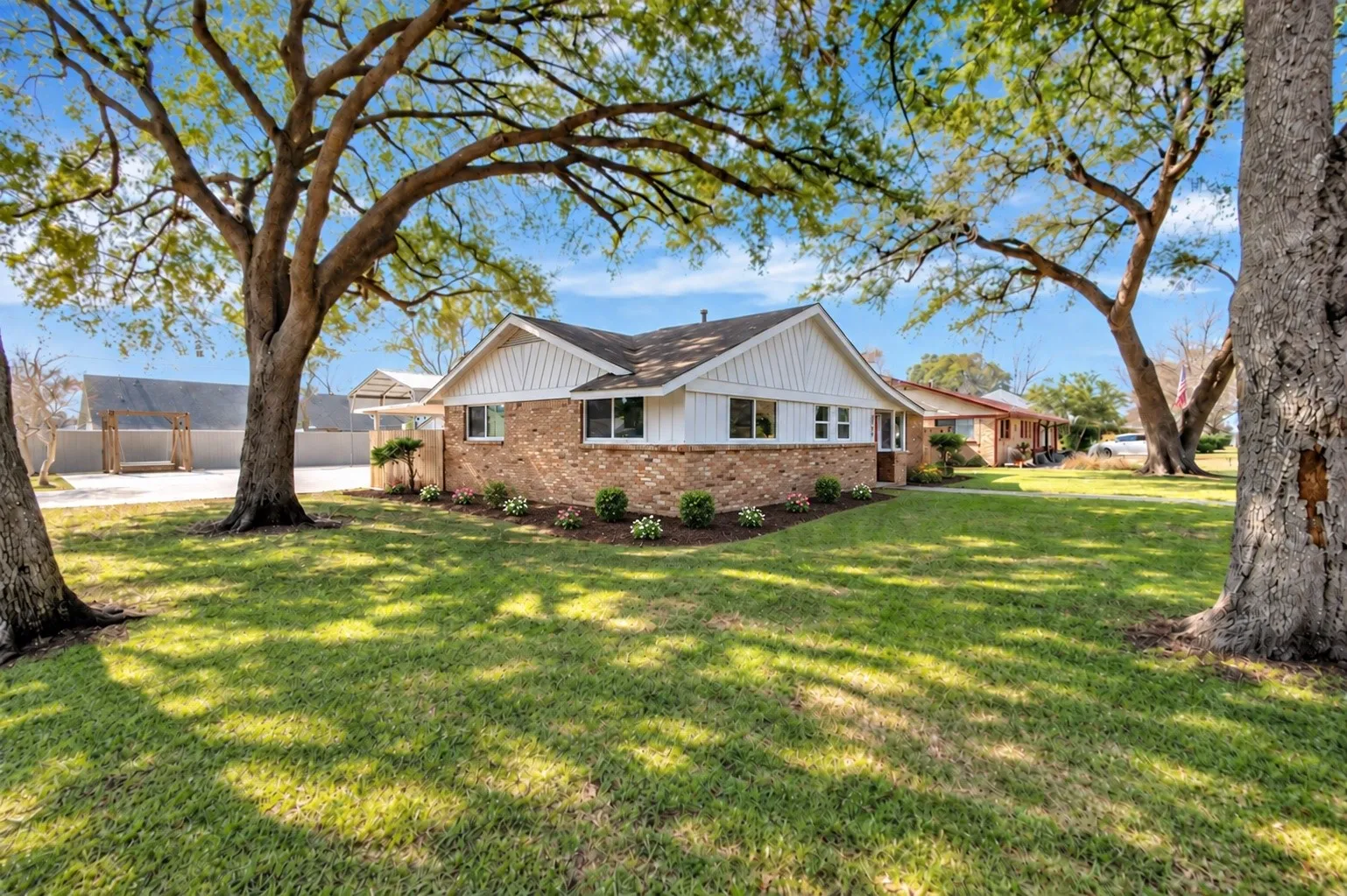 Brick and siding exterior with mature trees and a manicured lawn