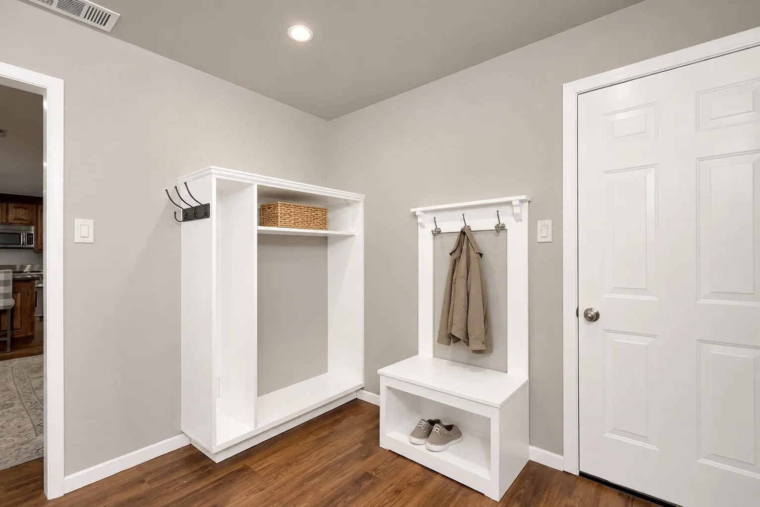 Wood-finish flooring with light gray walls, a white paneled door, and built-in white storage solutions