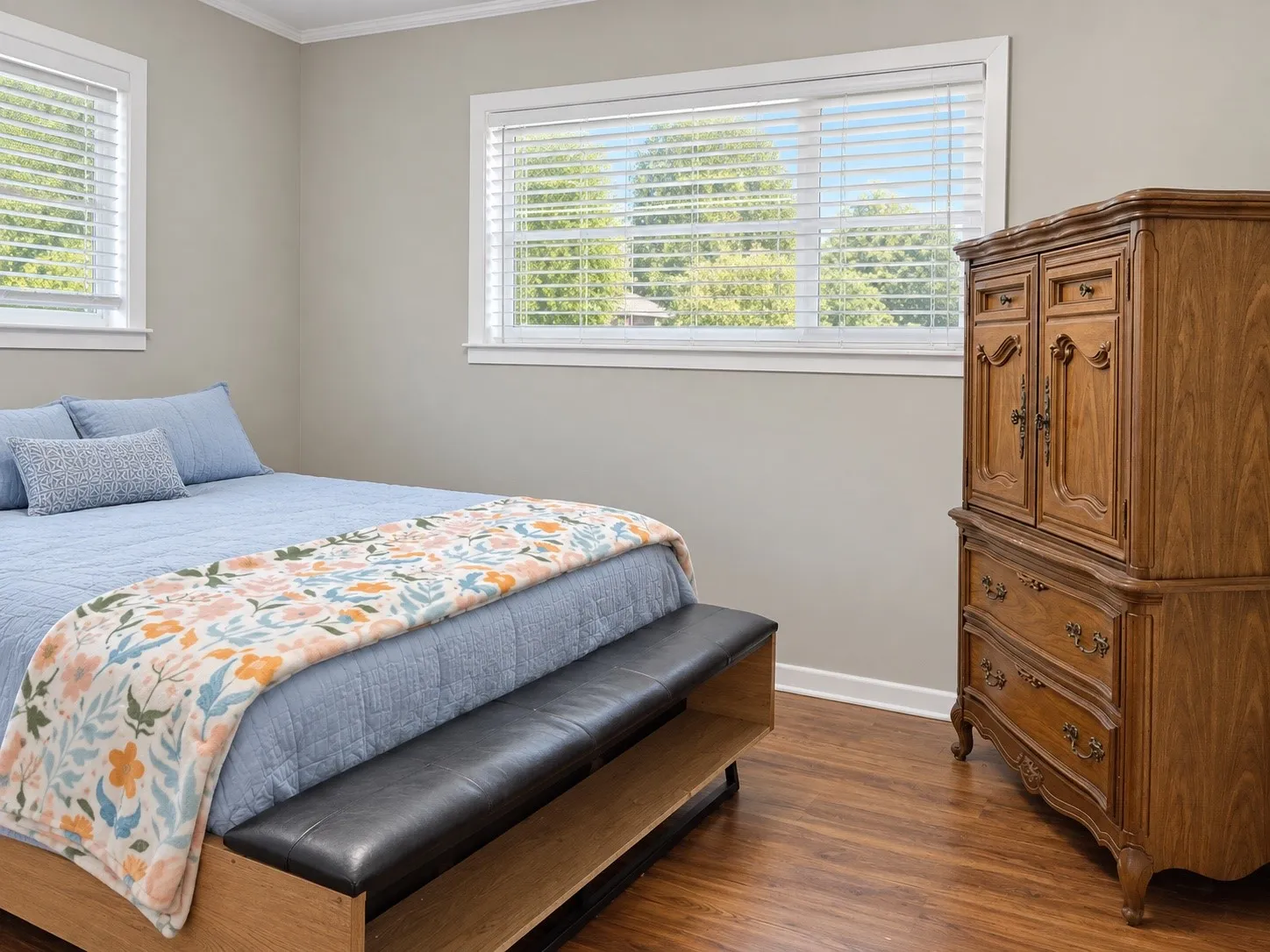 Light gray wall paint, wood-finish flooring, and two windows with blinds