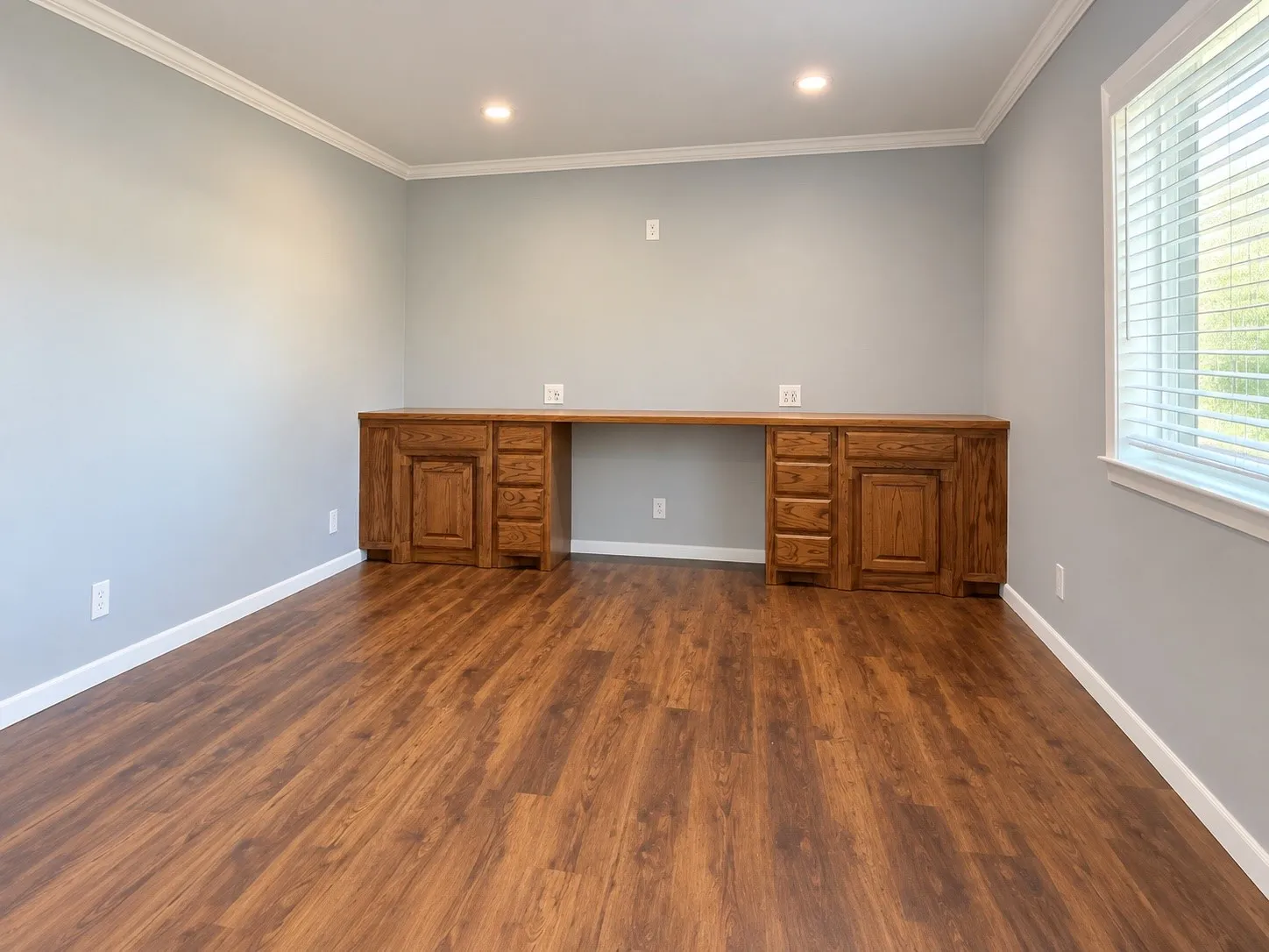Den/2nd Living or 4th Bedroom Built-in desk with wood-finish cabinetry, wood-finish flooring, recessed lighting, crown molding, and window with blinds