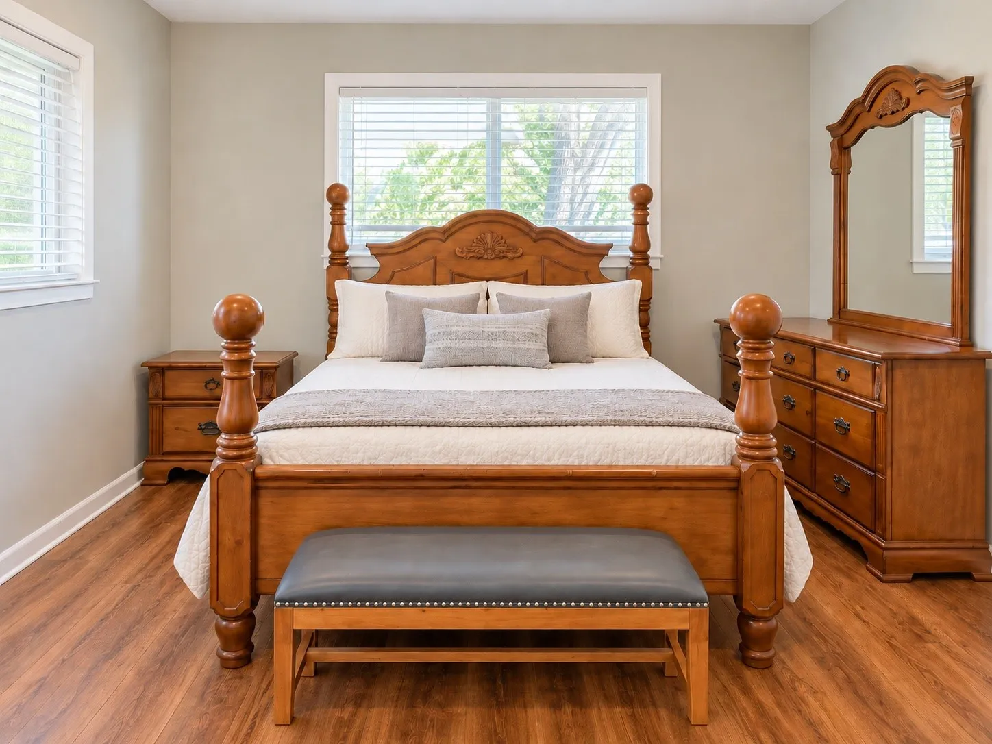Master bedroom showcasing a four-poster wood bed with turned finials and carved headboard, complemented by matching wood nightstands and a coordinating dresser with mirror