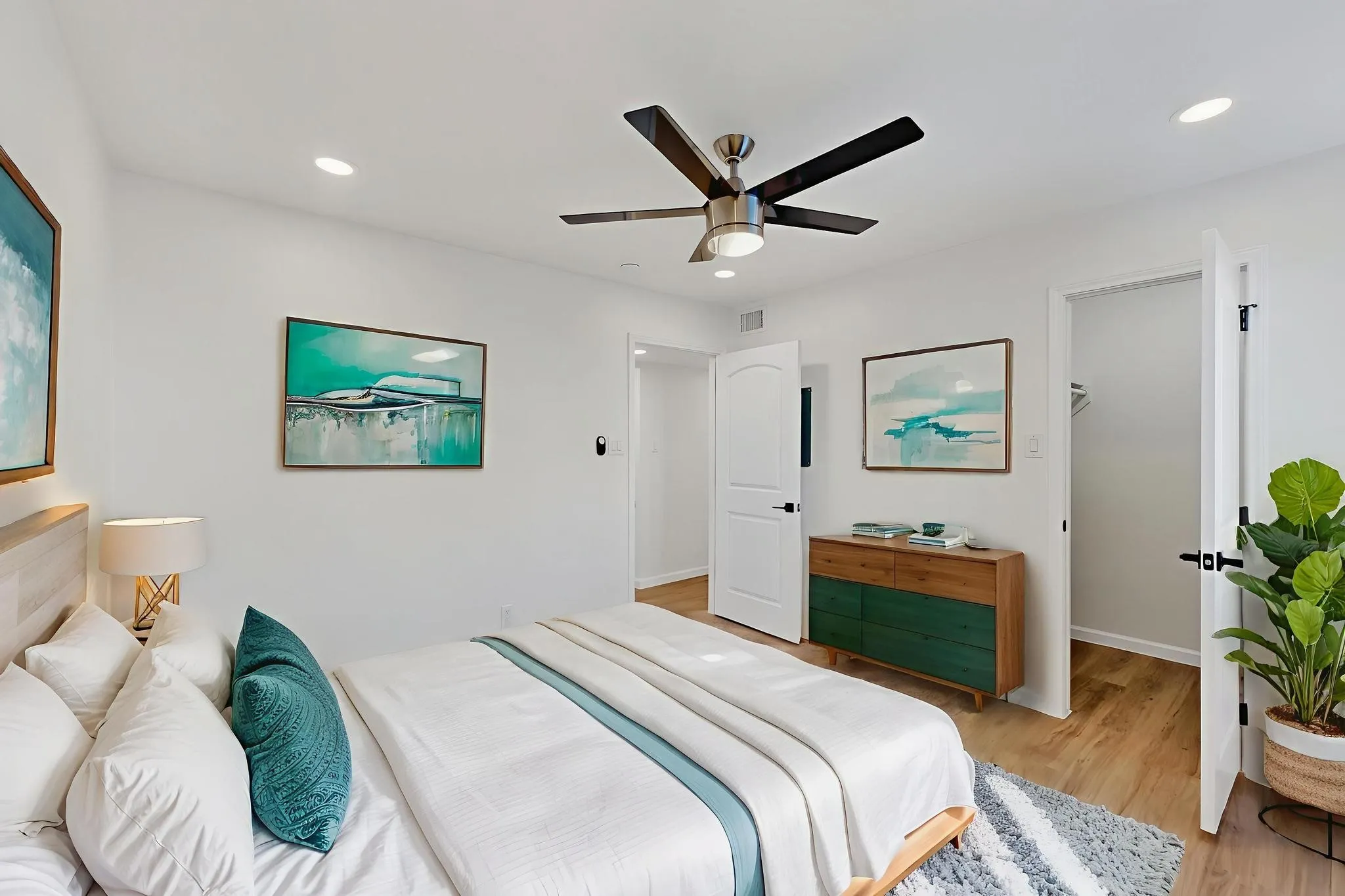 Recessed lighting illuminates this bright room featuring wood-finish flooring and a contemporary ceiling fan