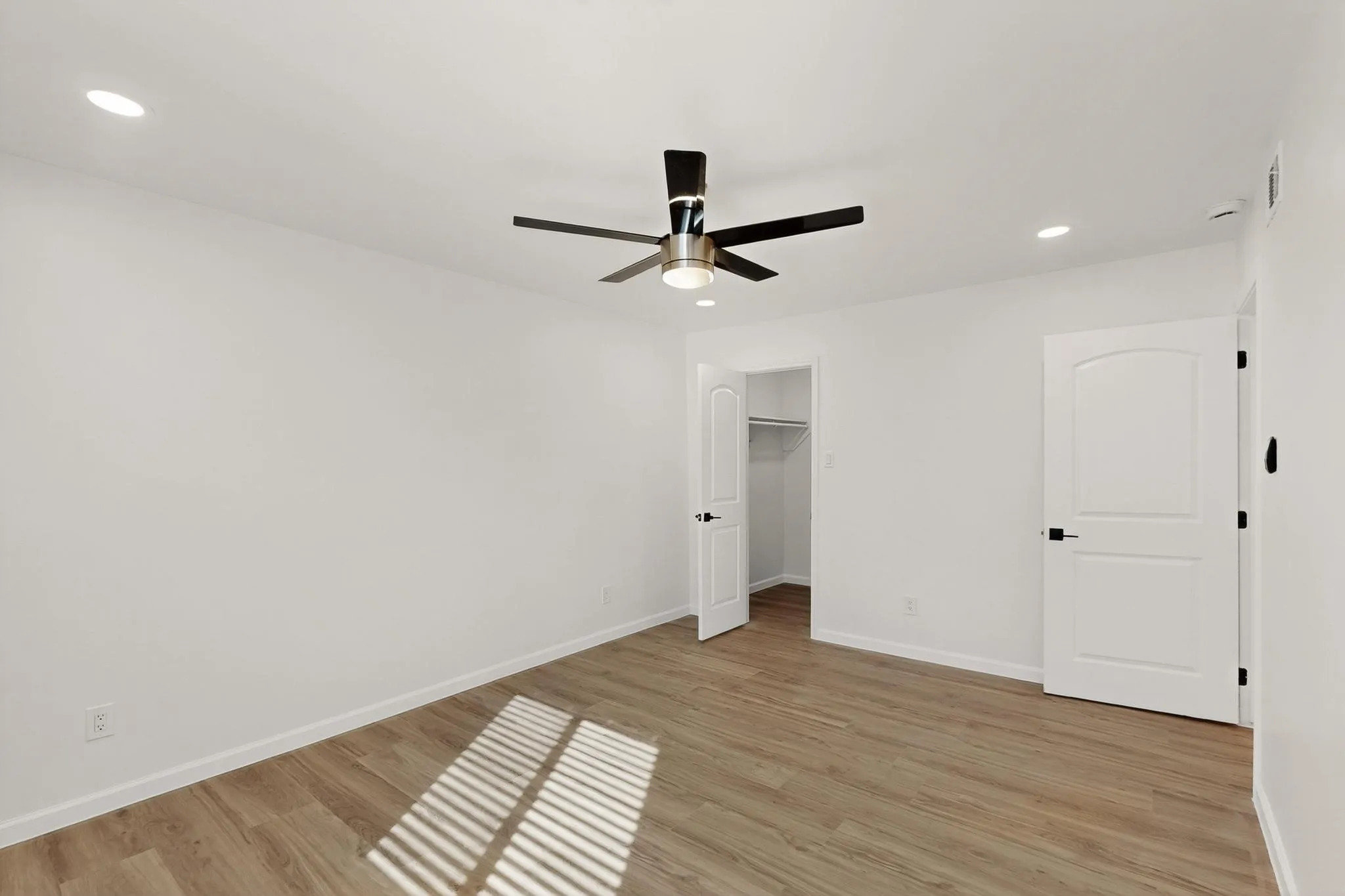 Recessed lighting, wood-finish flooring, ceiling fan, white interior doors, and built-in closet shelving
