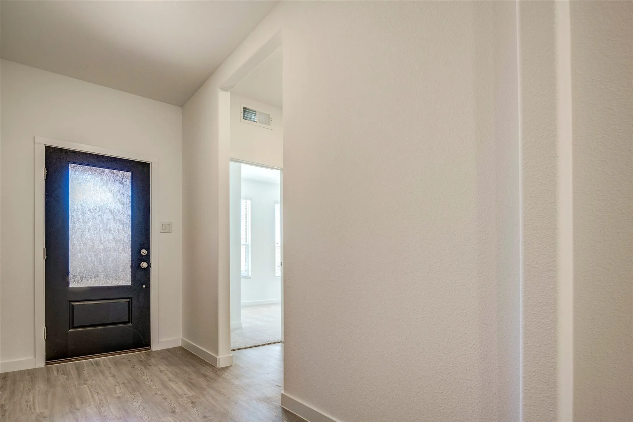 Beautiful dark colored front door with frosted glass, LVP flooring, spacious entry with white walls....
