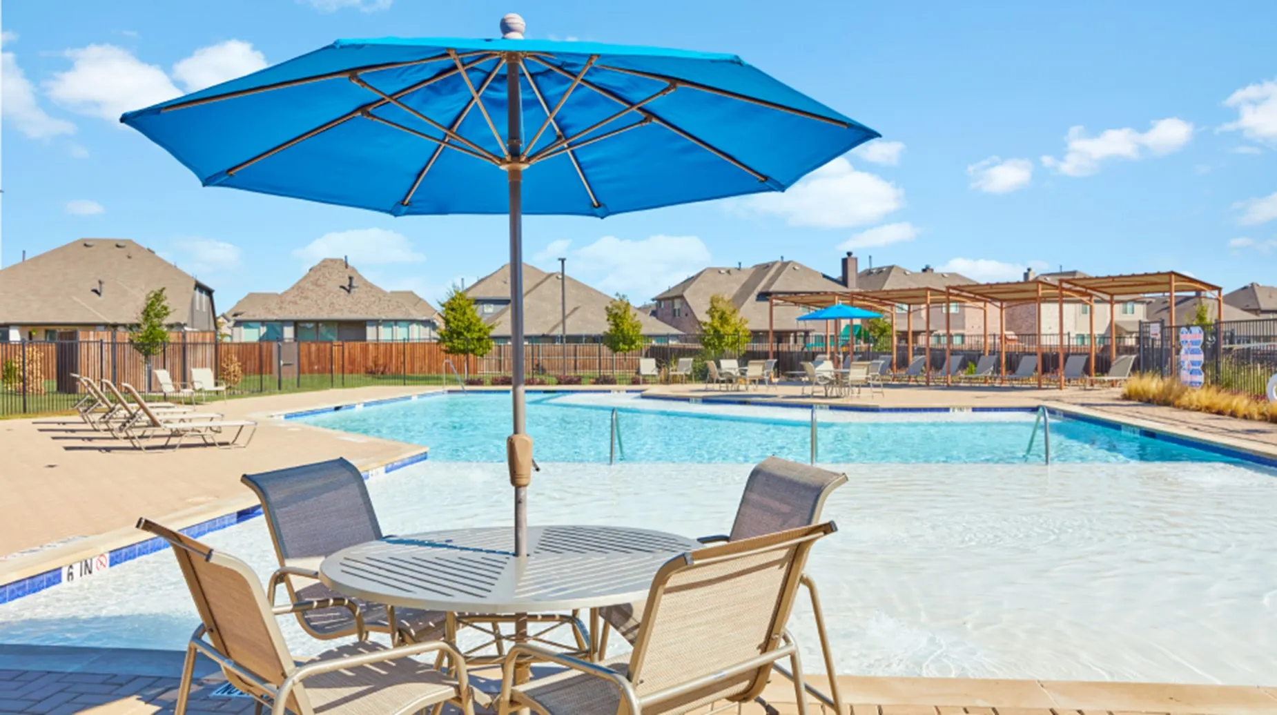 Community outdoor swimming pool with integrated tanning ledge and surrounding paved patio....imagine relaxing here......