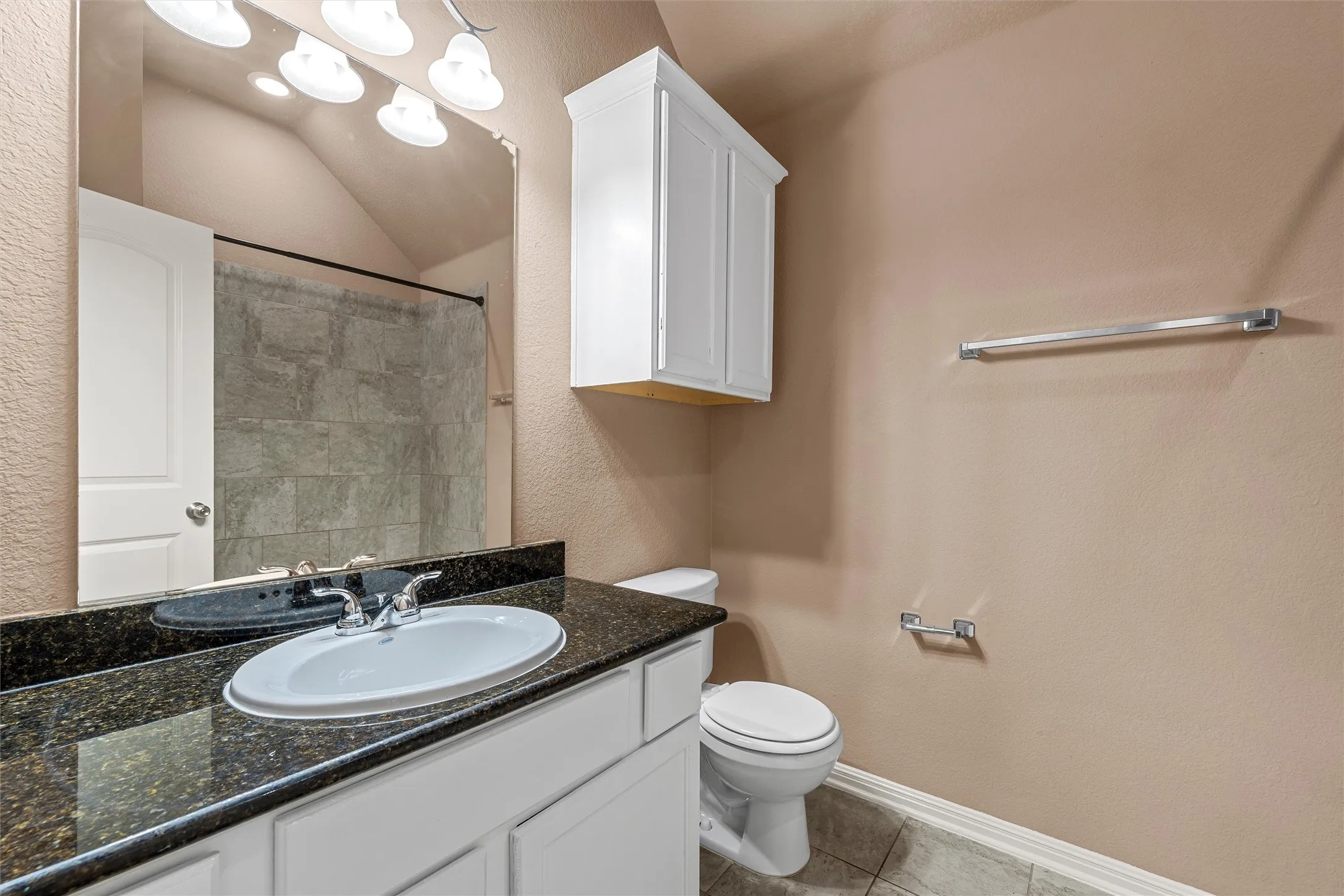 Vanity with dark speckled countertop, white cabinetry, and an undermount sink