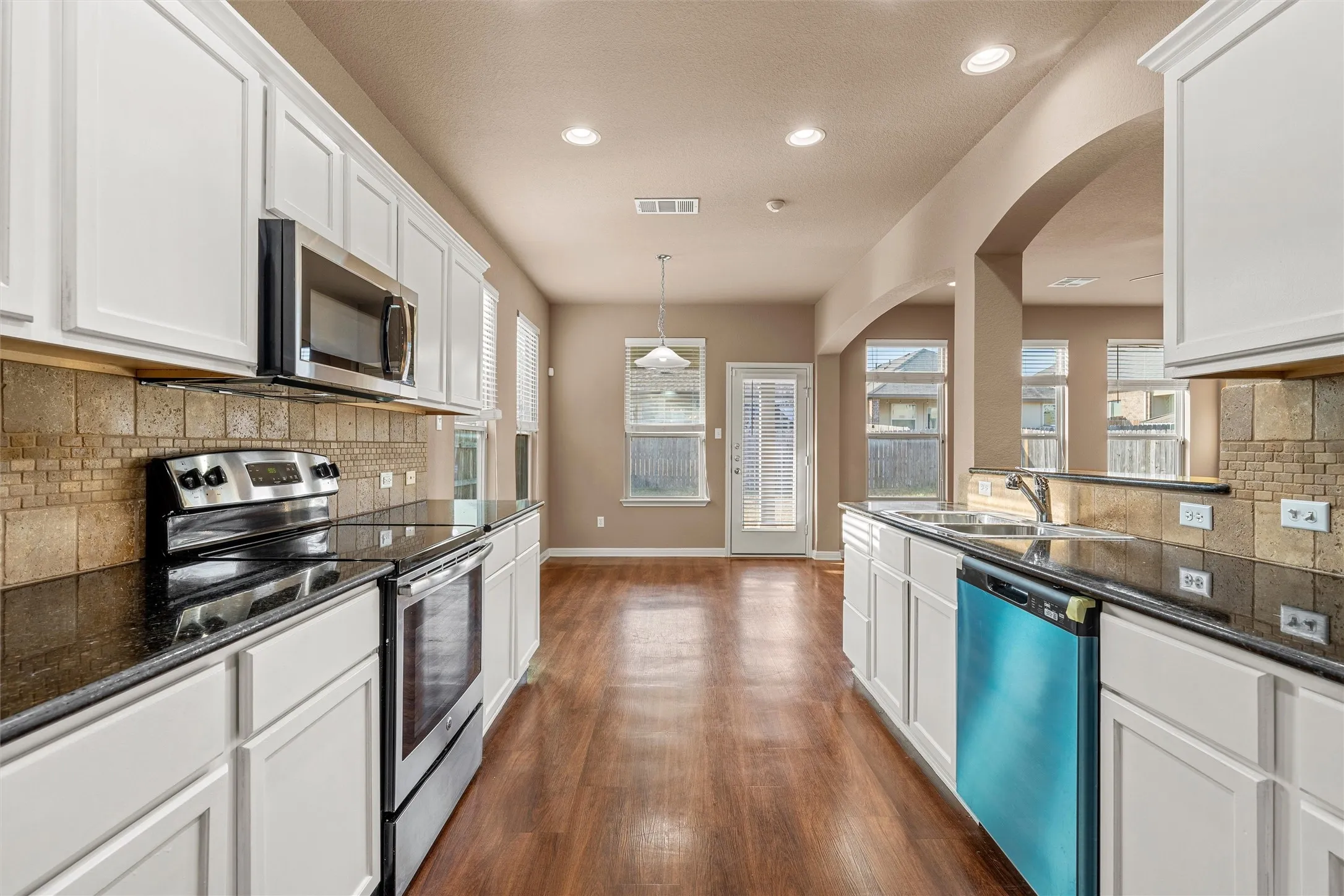 Modern kitchen featuring white cabinetry, dark countertops, and stainless steel appliances