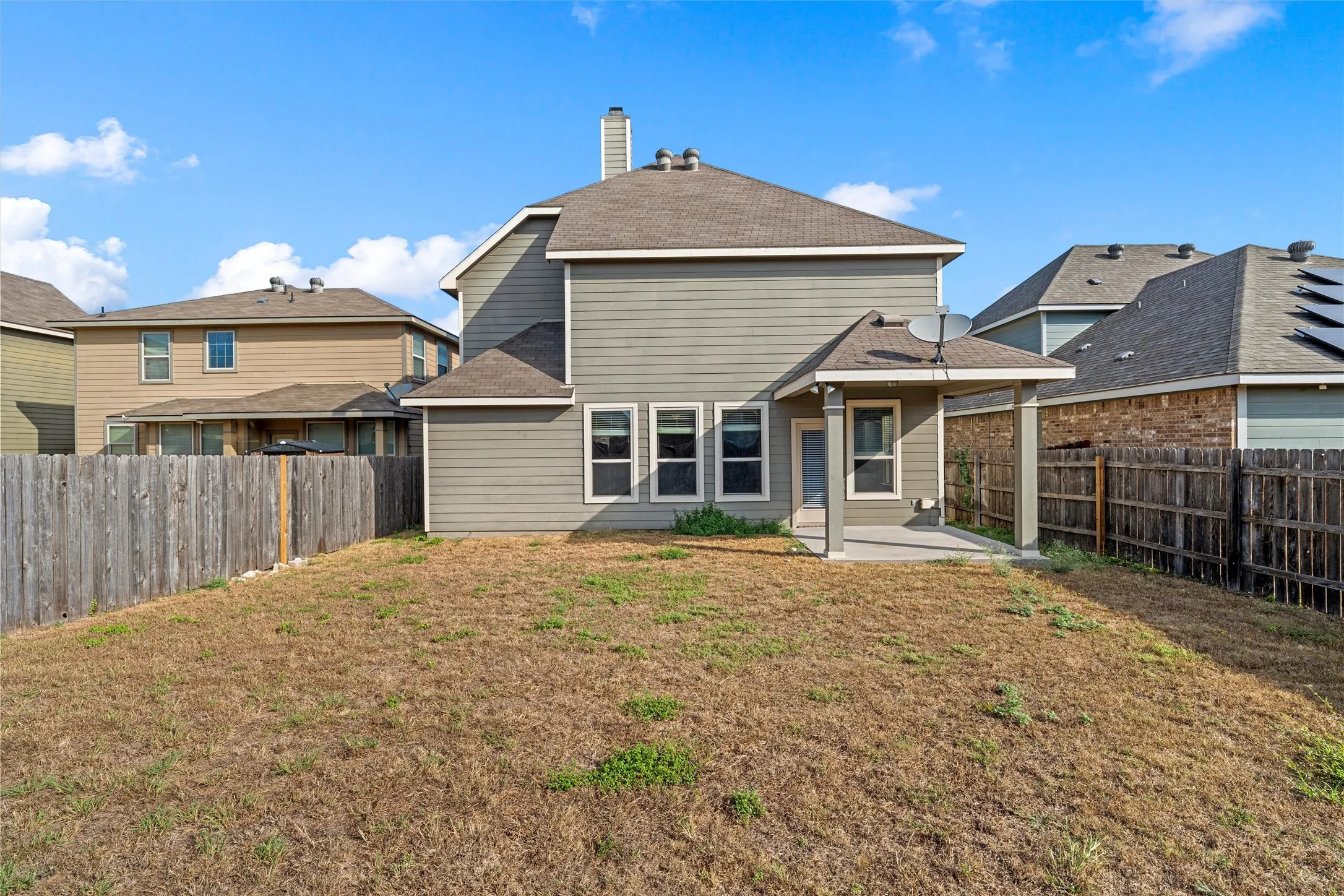 Rear exterior with covered patio, multiple windows, and horizontal siding