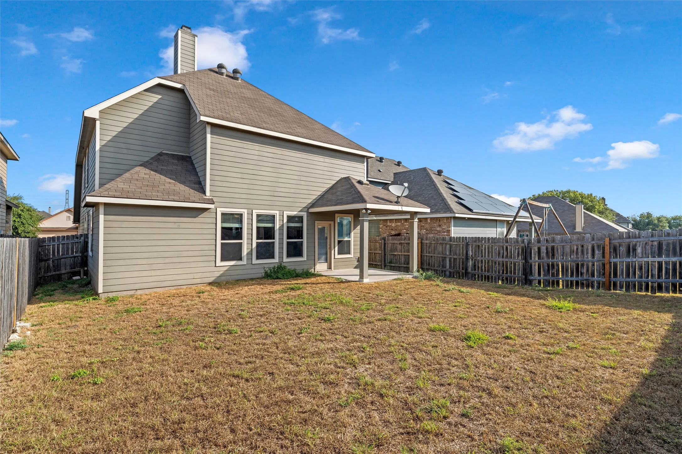Exterior features include a covered patio, multiple windows, and a fenced perimeter