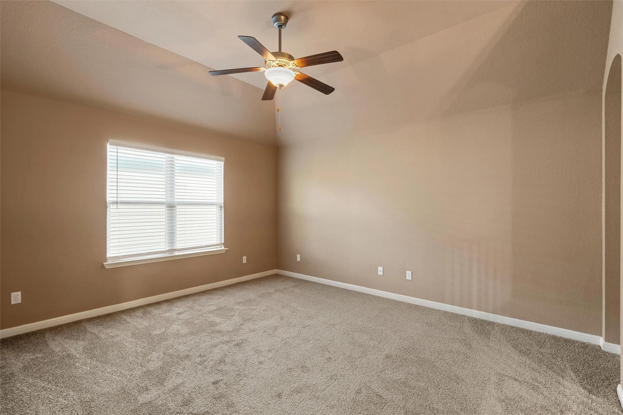 Vaulted ceiling with an attached ceiling fan, neutral carpet flooring, and a window with blinds