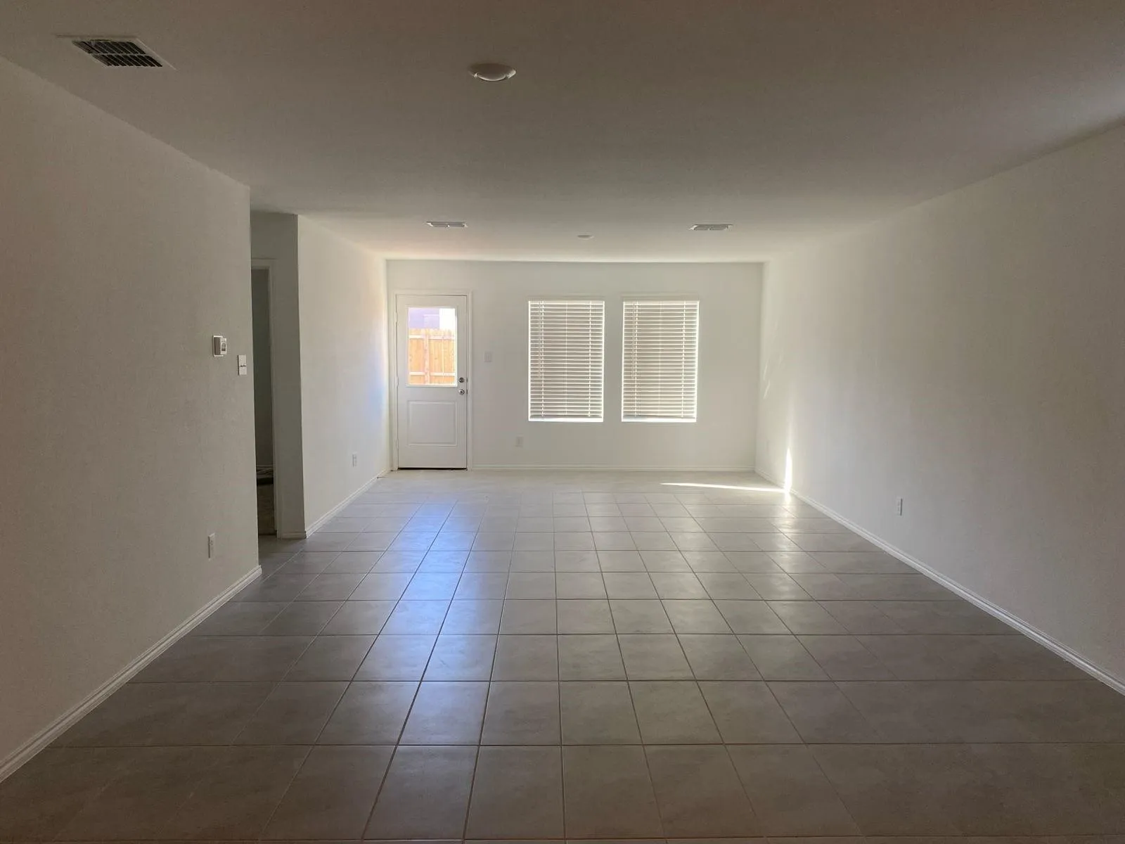 Recessed lighting, tile flooring, multiple windows with blinds, and a white paneled door