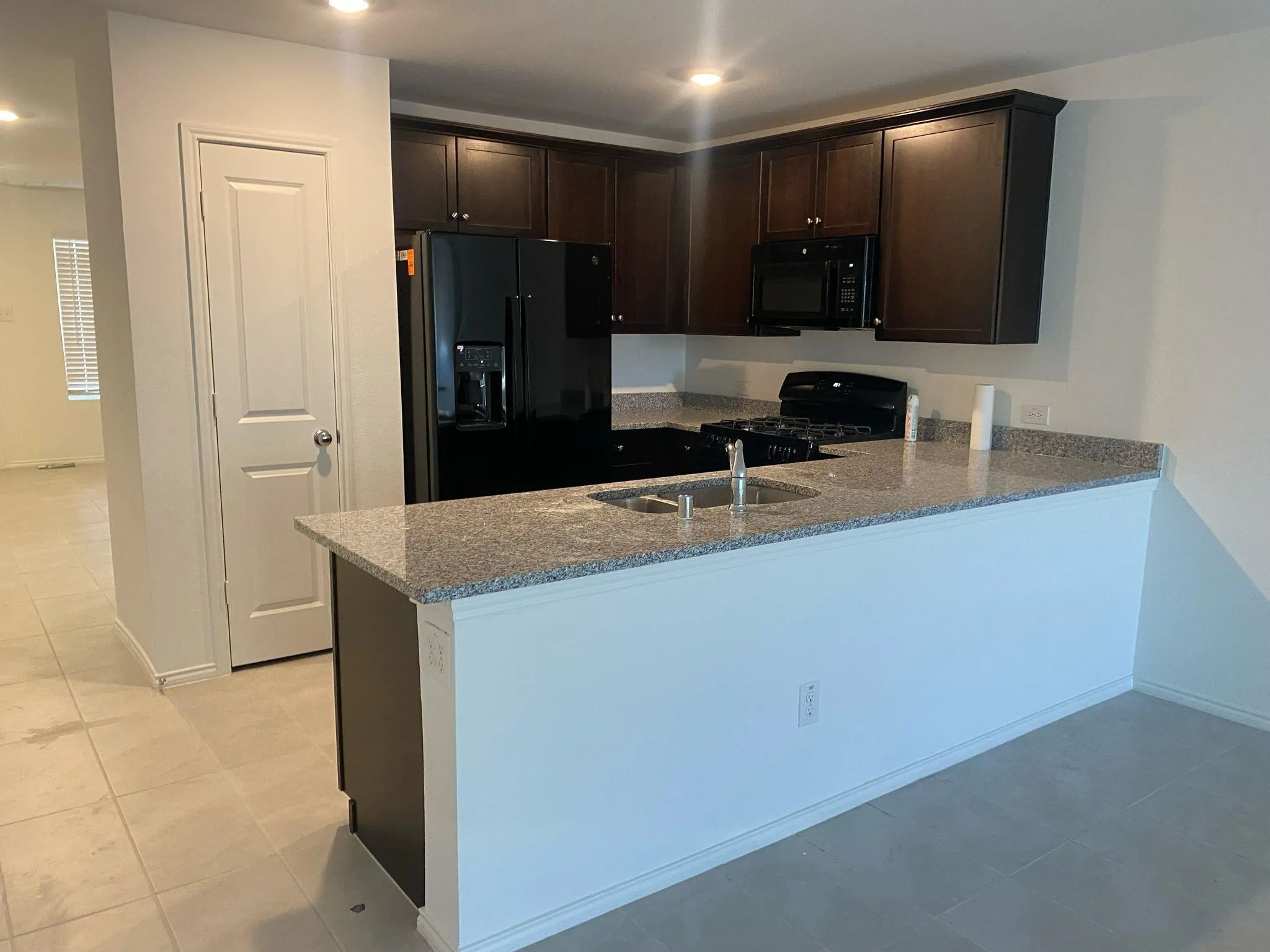 Kitchen with granite countertops, dark wood-finish cabinetry, a built-in microwave, and a gas range
