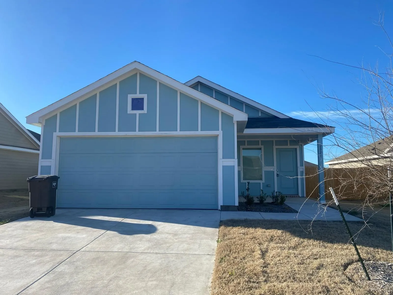 Light blue siding with white trim, a covered front porch, an attached garage, and a concrete driveway