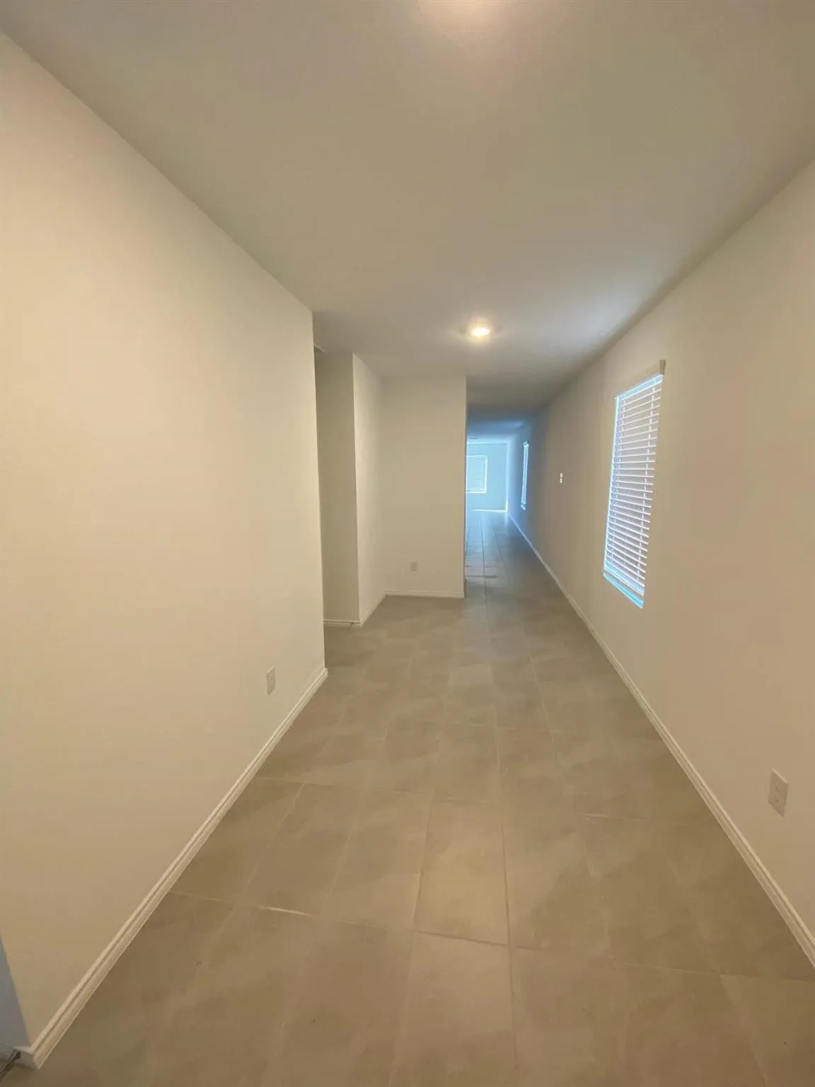Recessed ceiling lighting, neutral-toned walls, tile flooring, and window with blinds