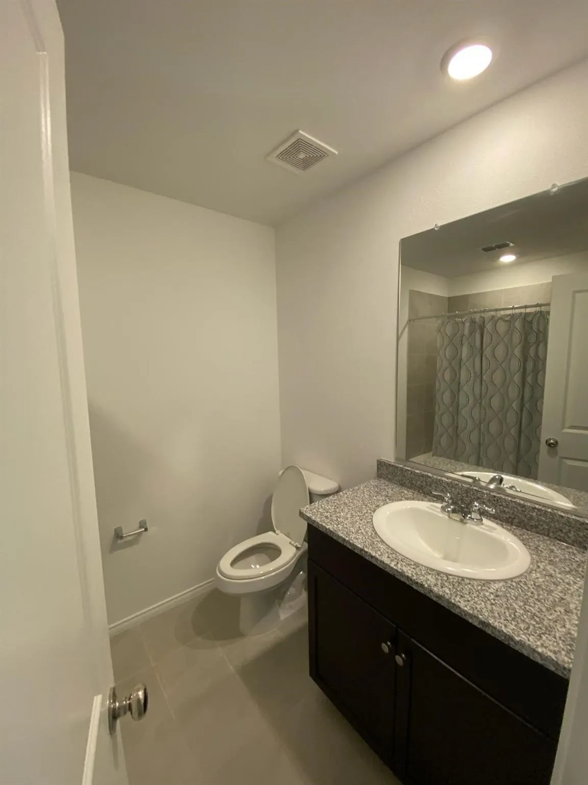 Dark wood-finish vanity with a granite countertop, undermount sink, and chrome faucet