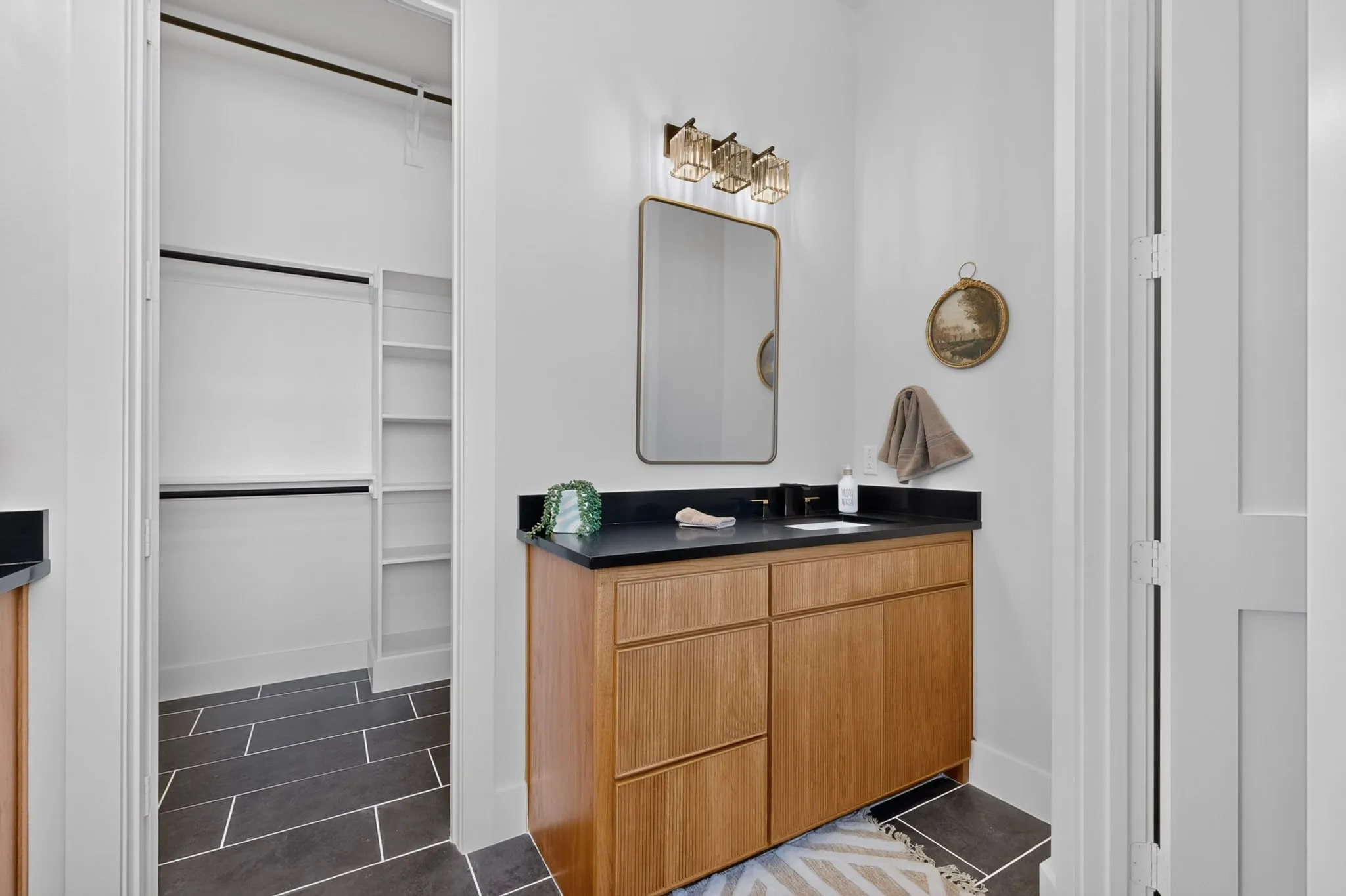 Vanity with wood-finish cabinetry and black countertop