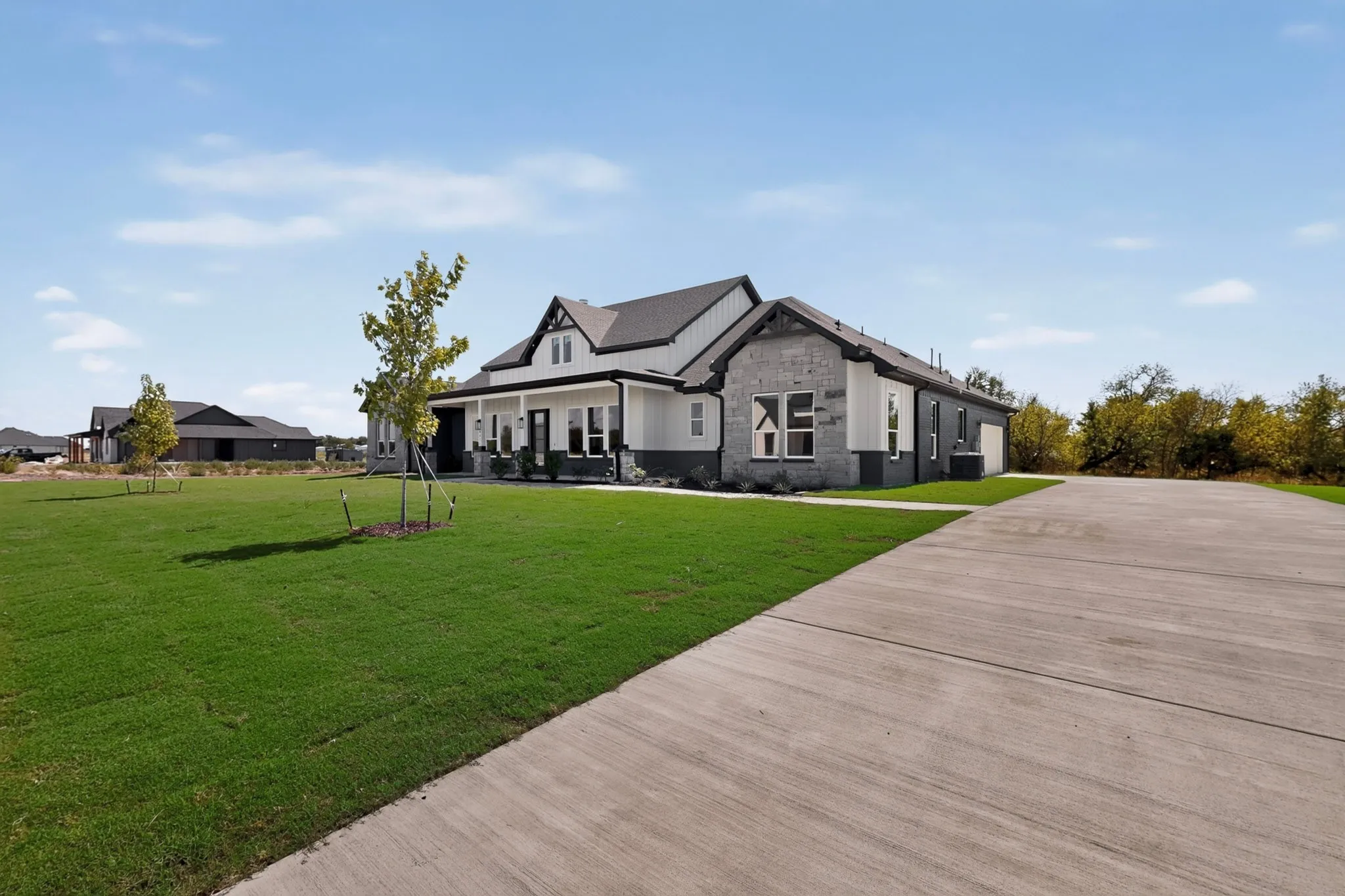 Exterior with a covered front porch, white siding, stone accents and beautiful driveway