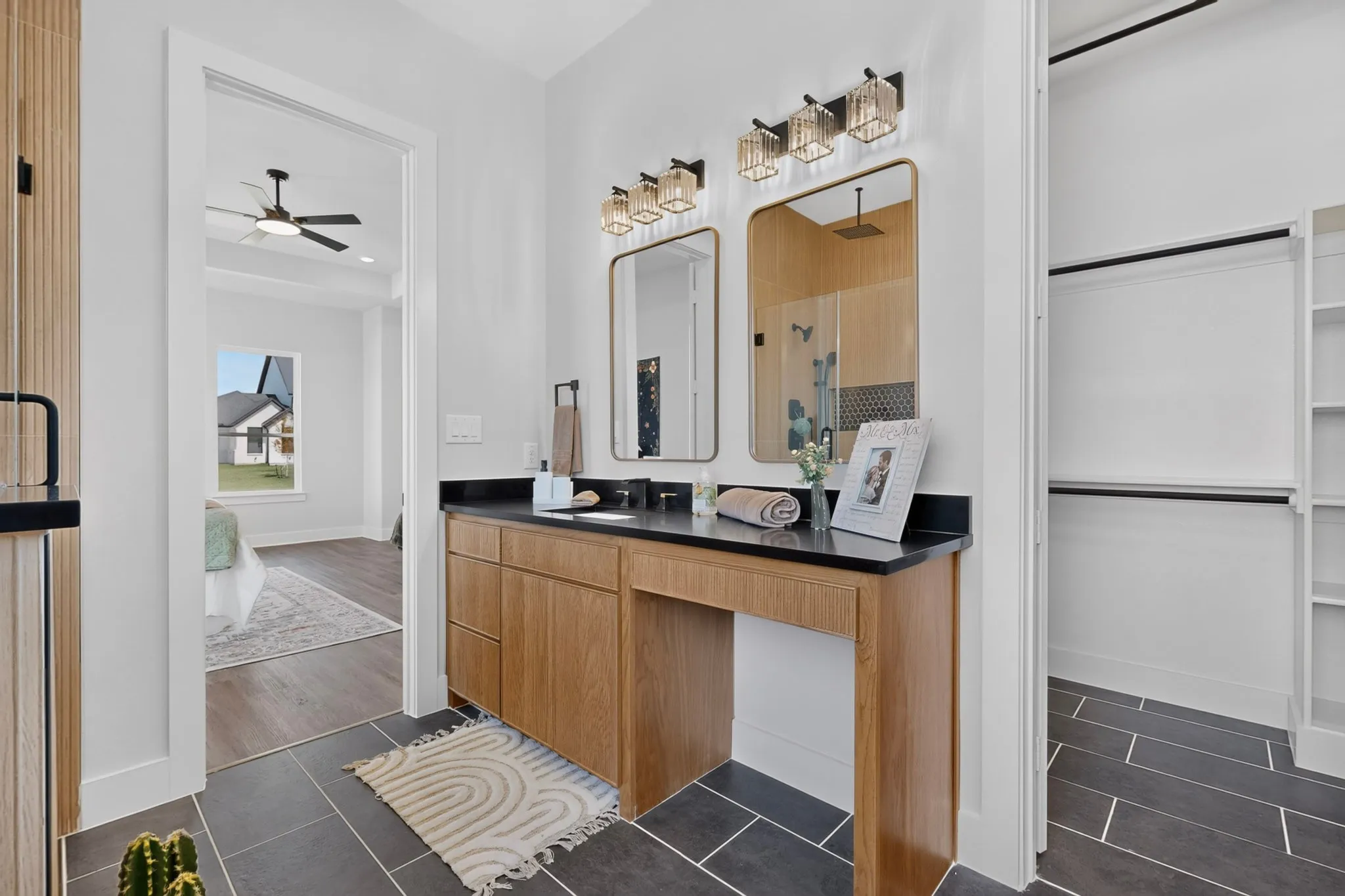 Dual vanity featuring wood-finish cabinetry & black countertops