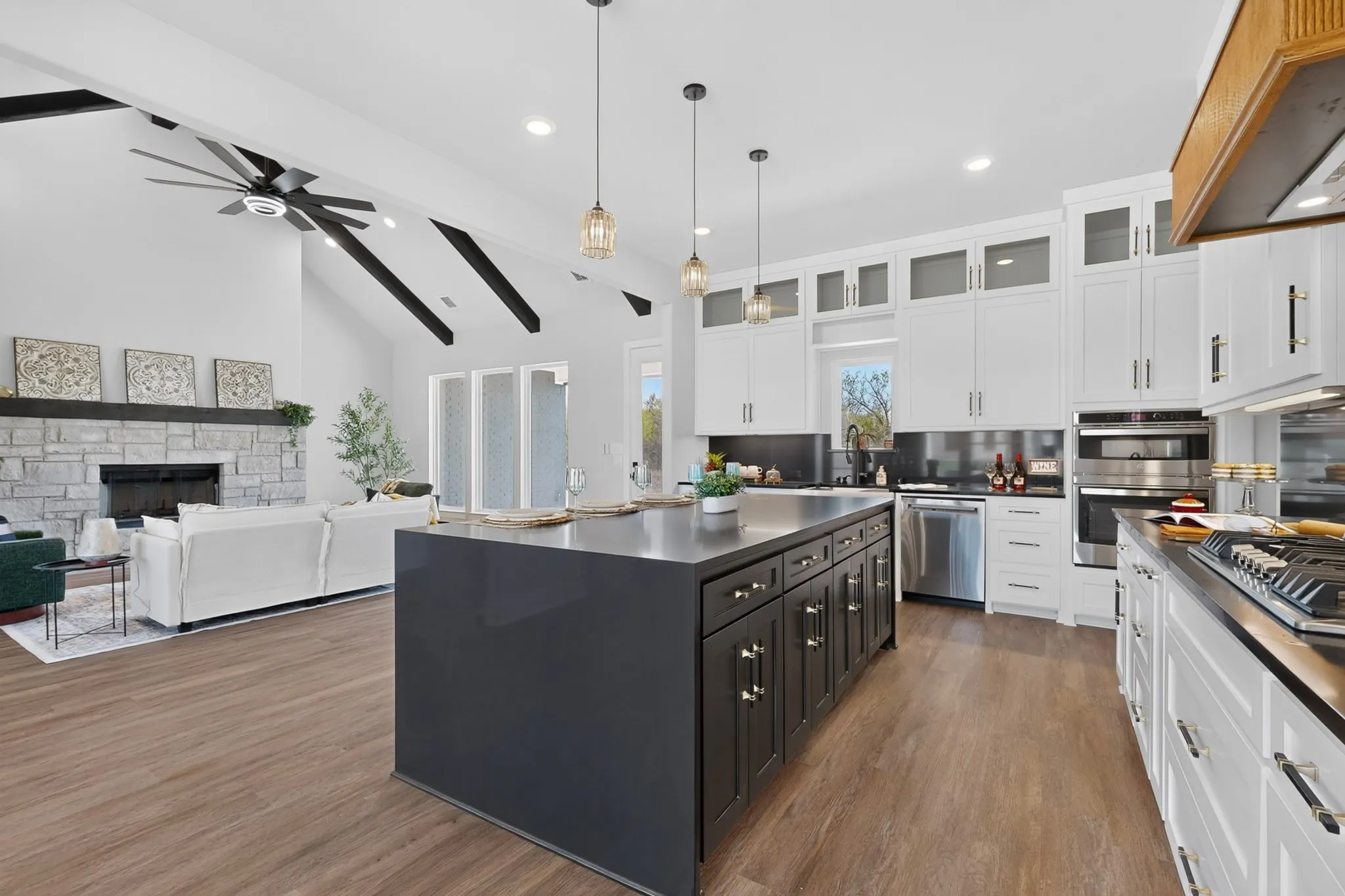 Spacious kitchen featuring an expansive center island with dark cabinetry, stainless steel appliances, and white upper cabinetry