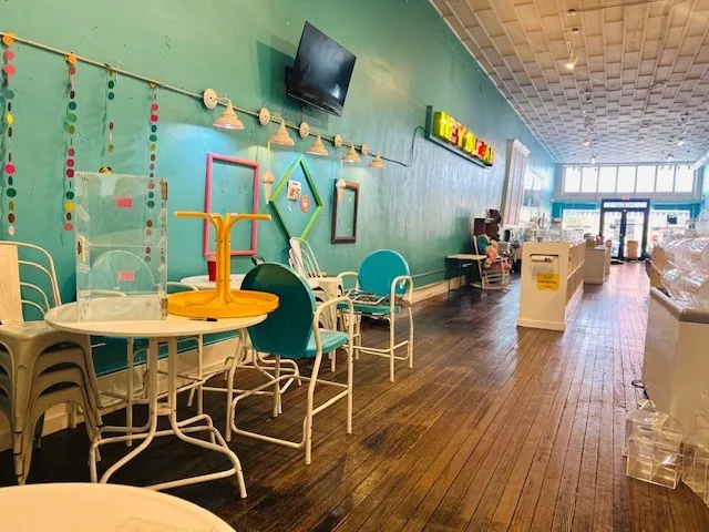 Hardwood flooring, painted wall surfaces, suspended ceiling tiles, wall-mounted lighting fixtures, and storefront entrance
