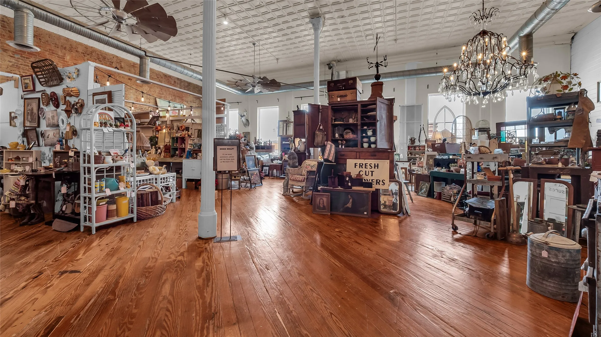 Exposed brick wall, wood-finish flooring, industrial ceiling fans, and a pressed tin ceiling
