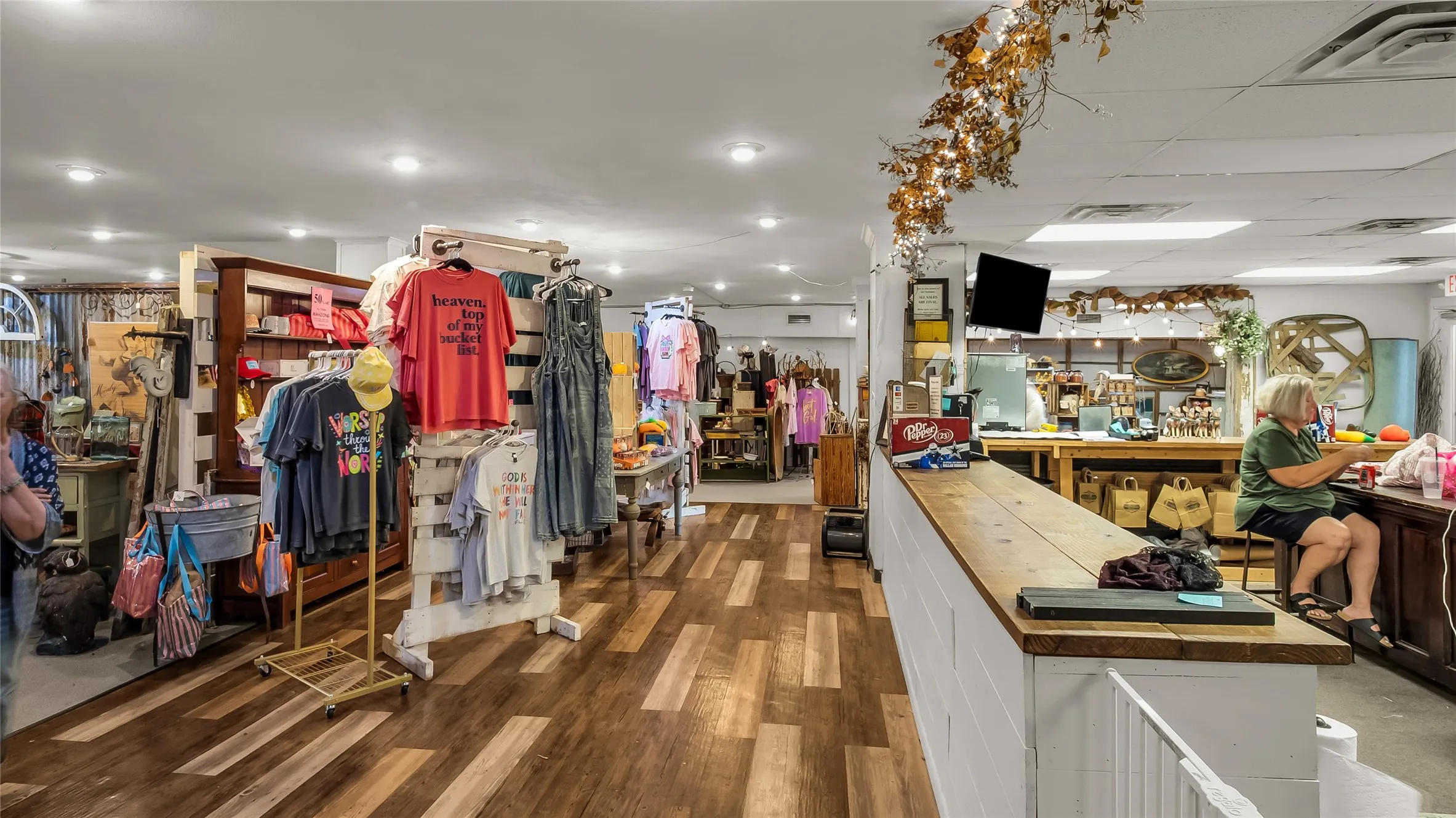 Expansive commercial space featuring wood-finish flooring, recessed lighting, and a white paneled sales counter with a wood-finish top