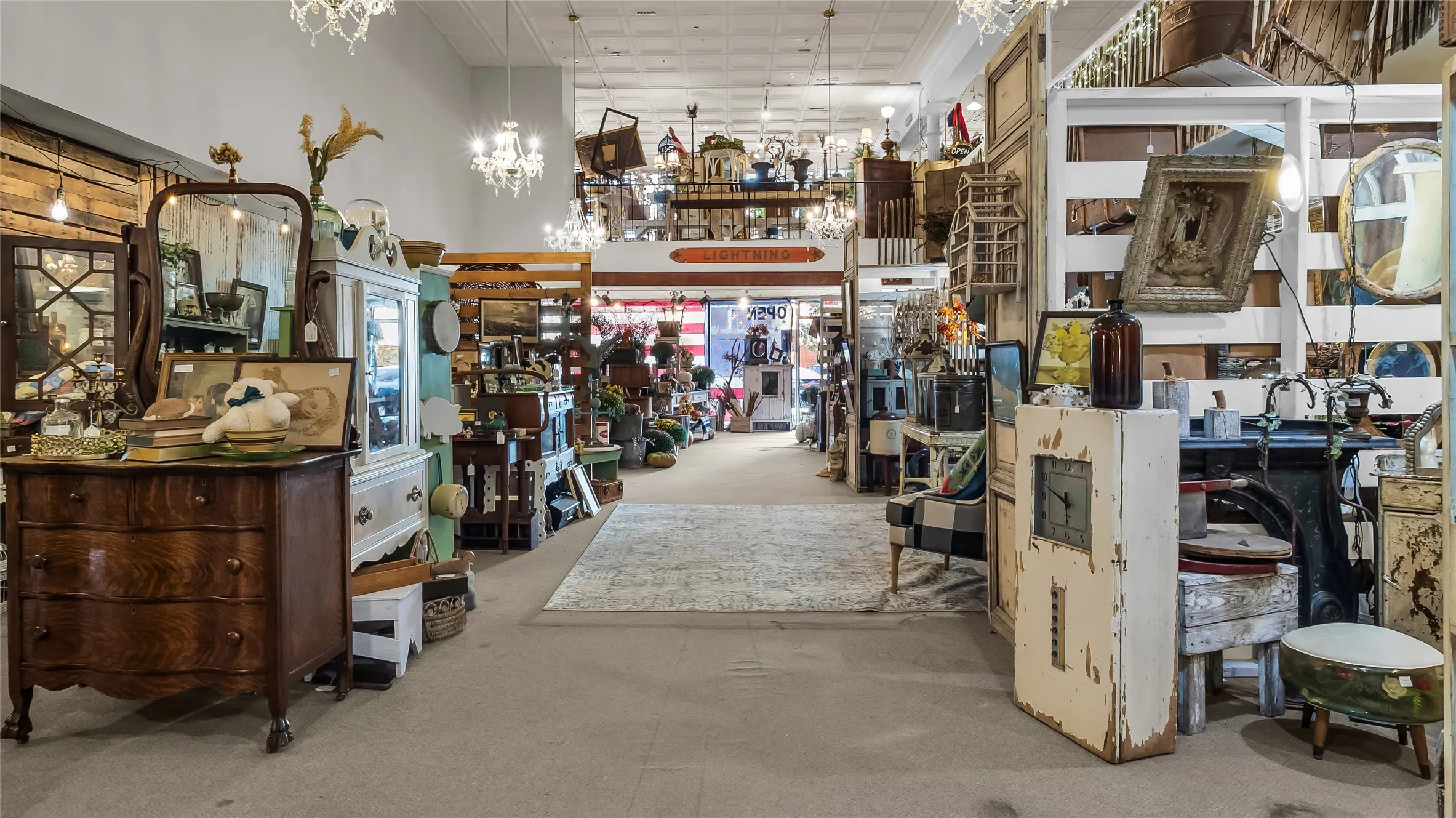 High ceilings with exposed grid, multiple decorative chandeliers, and a central area rug