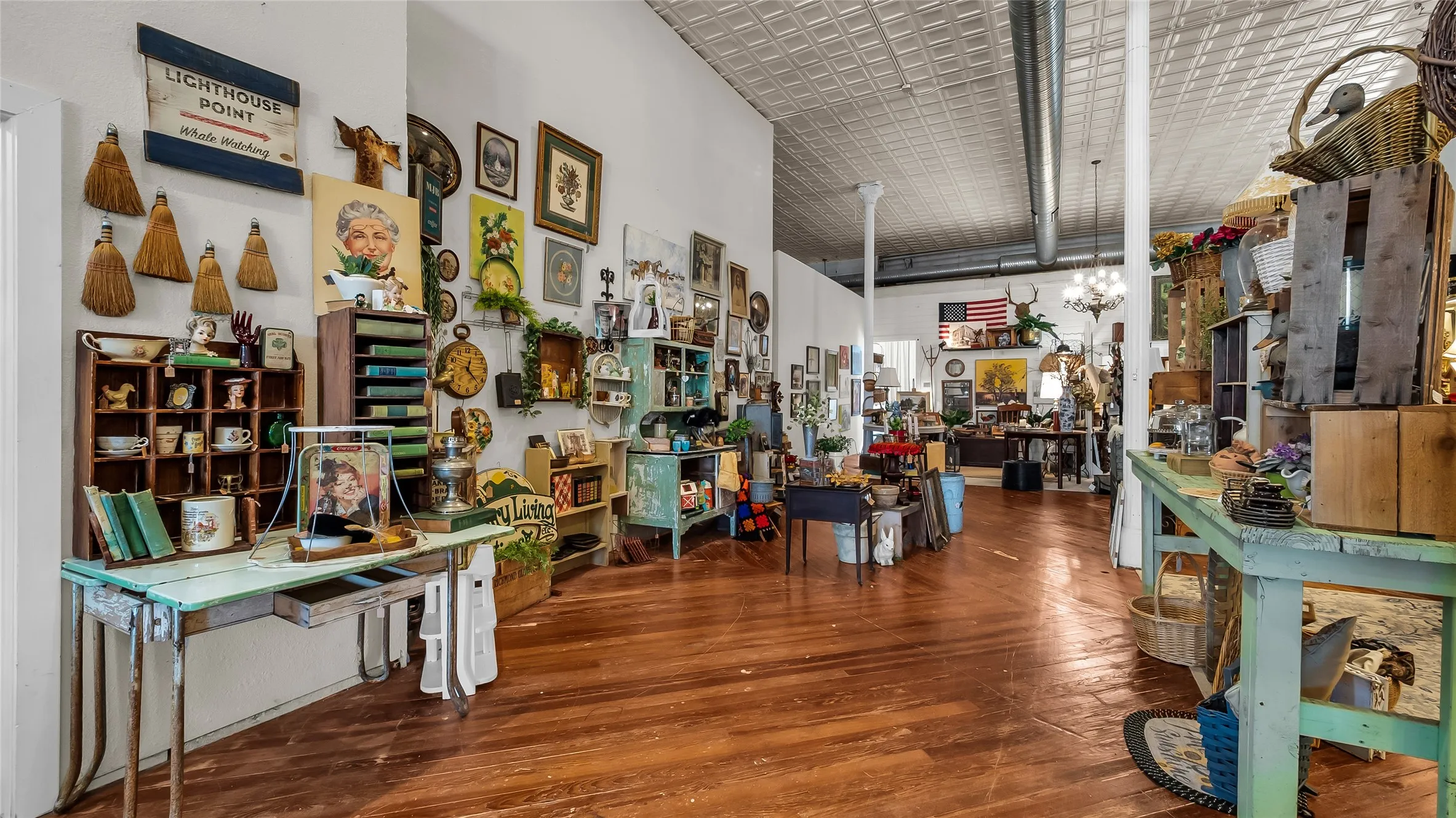 Expansive interior space featuring wood-finish flooring, high ceilings with tin-style tiles, and exposed ductwork