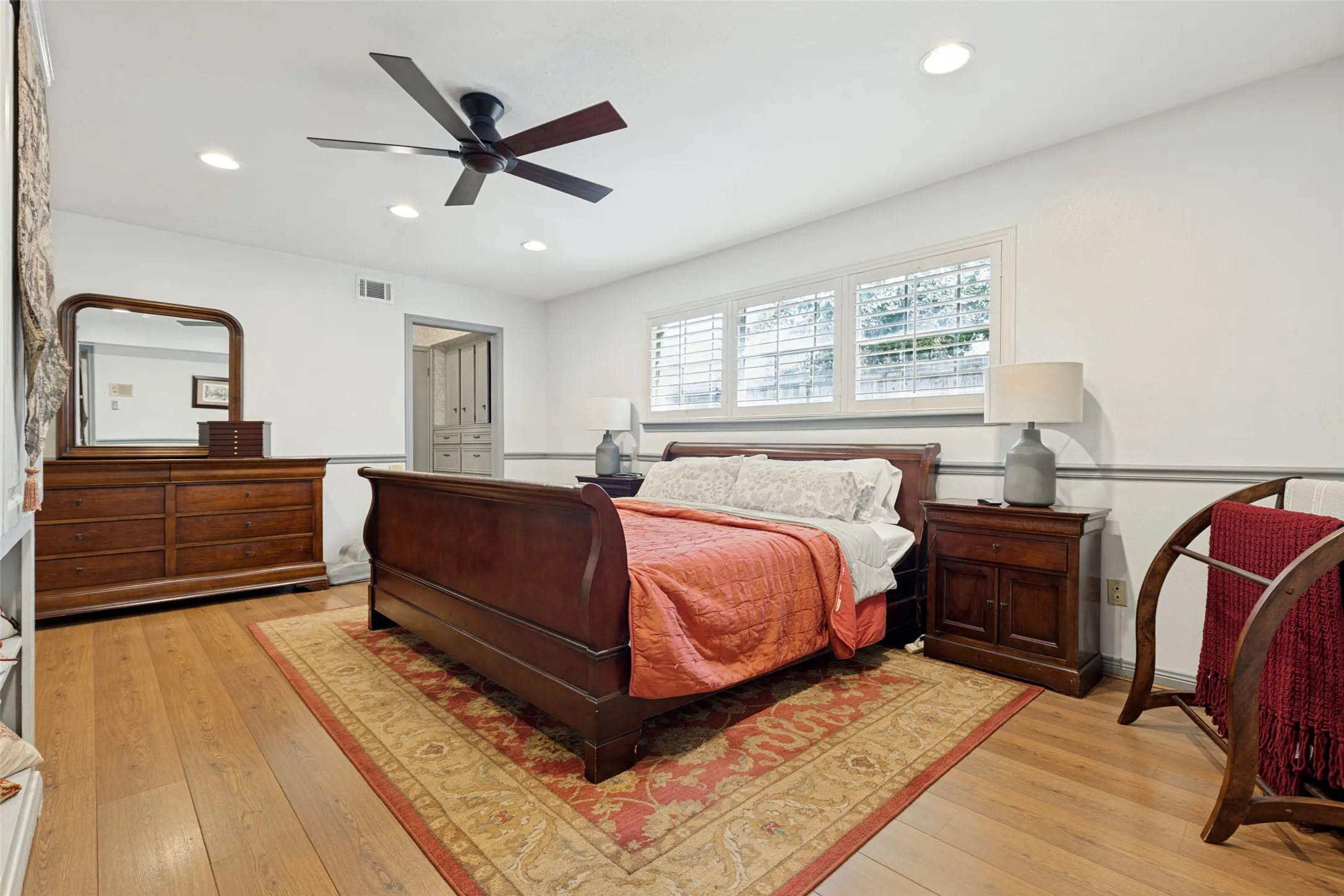 Recessed lighting, ceiling fan, wood-finish flooring, multiple windows with plantation shutters, and a chair rail molding