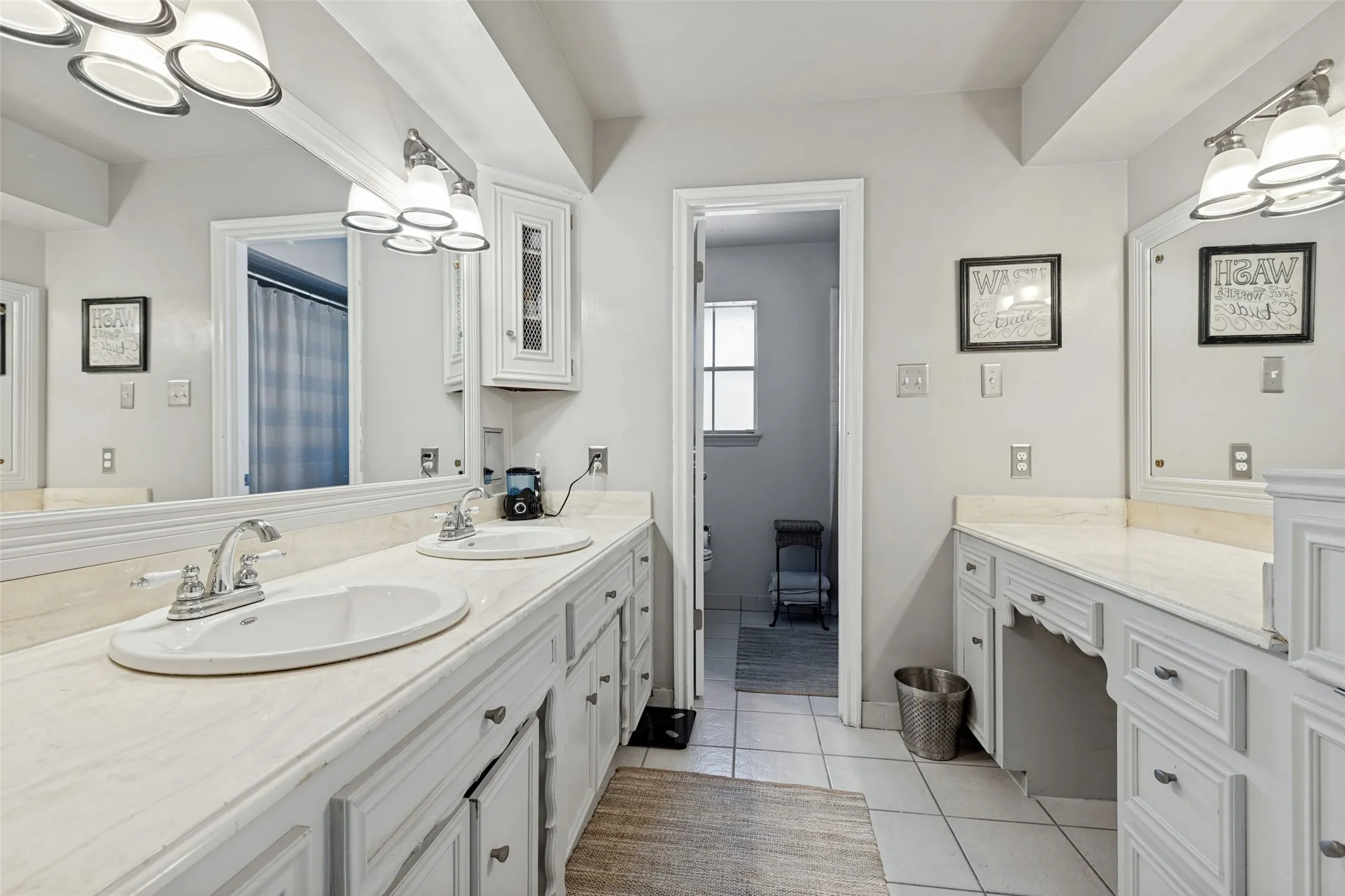 Dual vanity with undermount sinks, chrome fixtures, white cabinetry, and a built-in dressing table