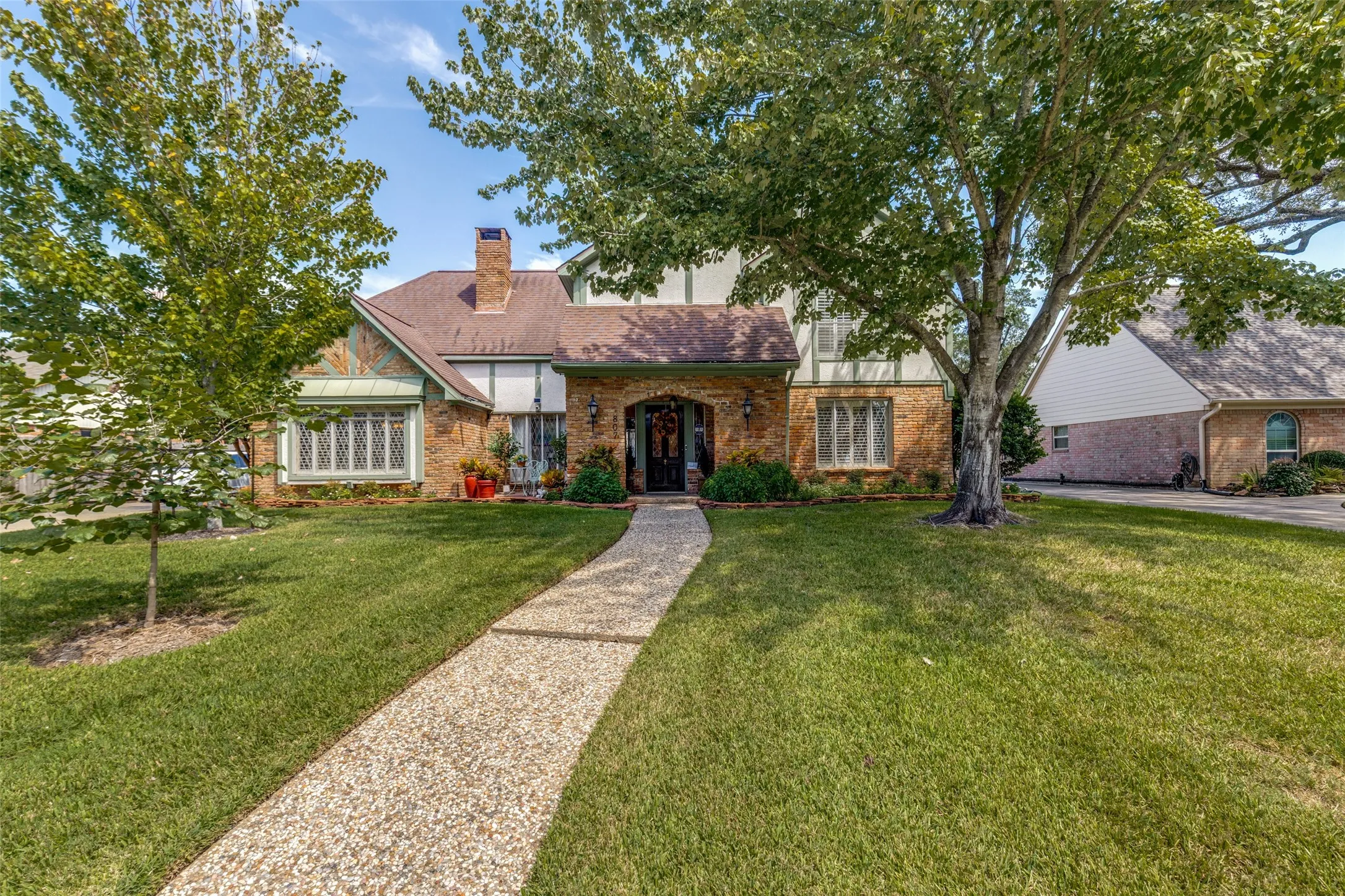Stone and brick exterior with a prominent chimney, gabled roofline, and arched entryway