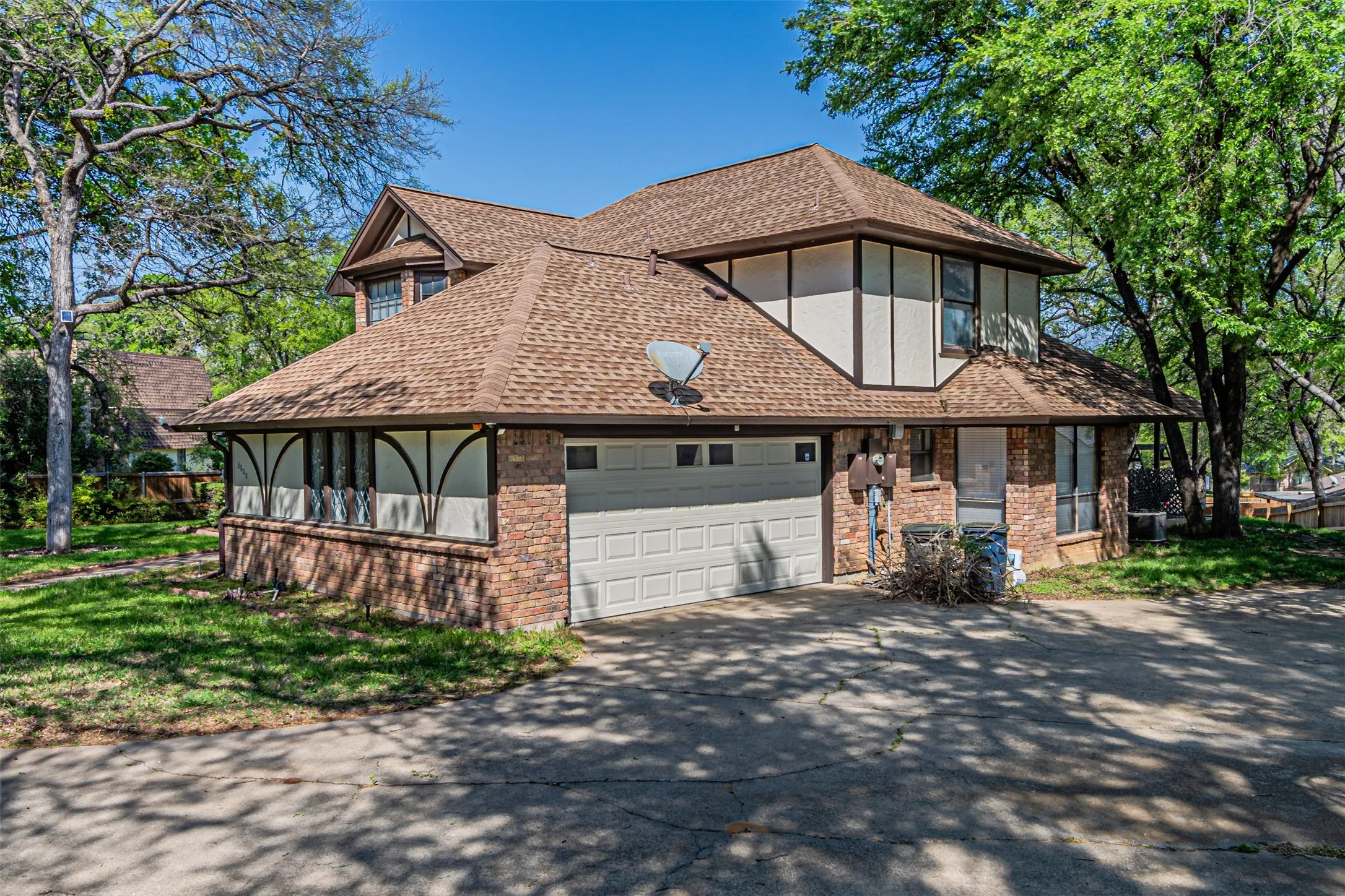Two-story property featuring a brick and siding exterior, multi-gabled roof, and attached two-car garage