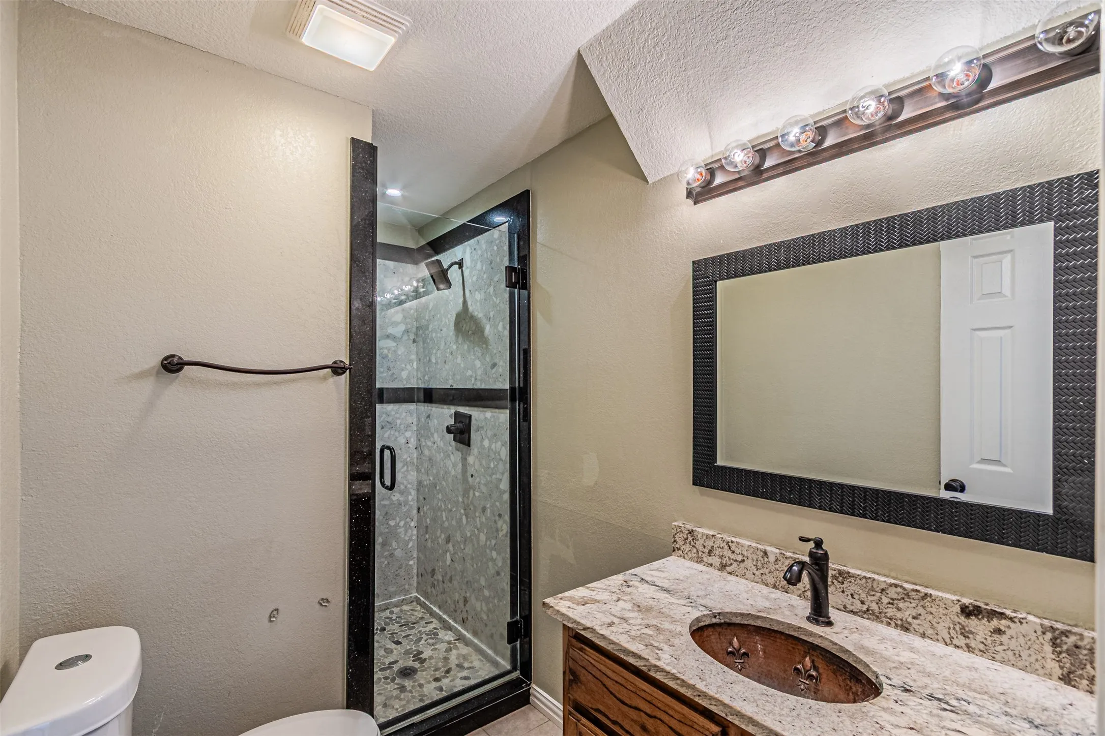 Walk-in shower with glass enclosure and pebble floor
