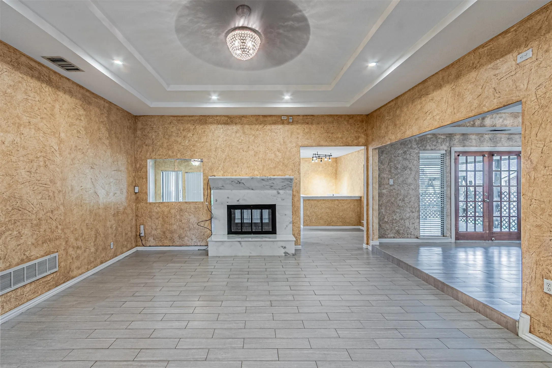 Tray ceiling with recessed lighting and a central chandelier