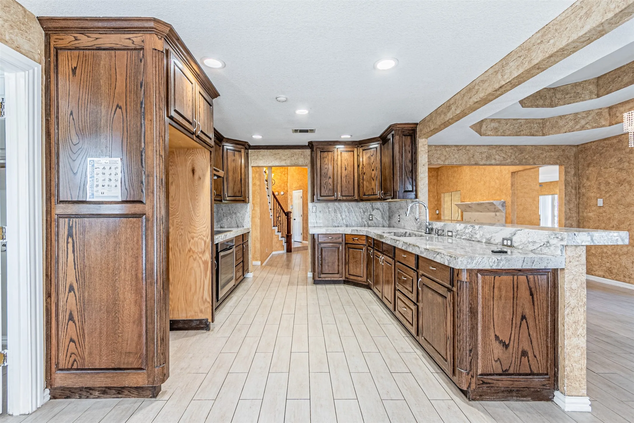 Wood-finish cabinetry, light-toned flooring, integrated sink, and granite countertops