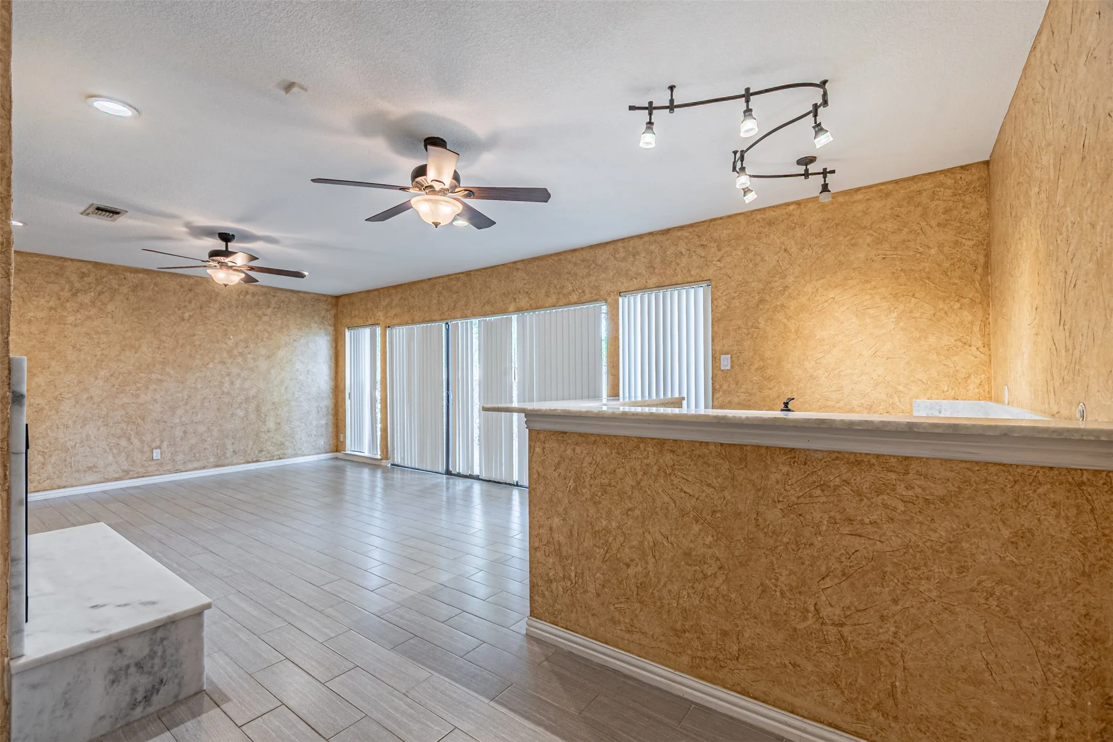 Wood-finish flooring throughout, two ceiling fans with integrated lighting, recessed lighting, and track lighting